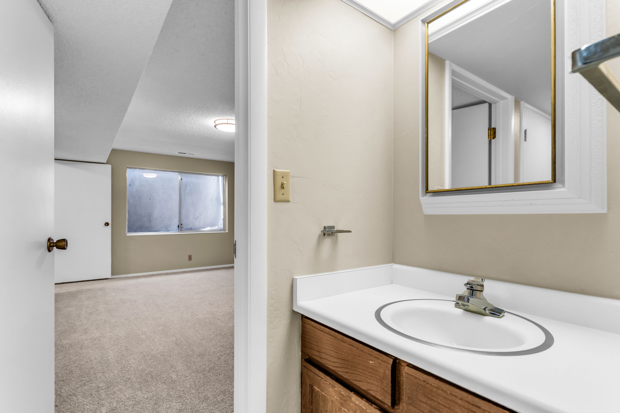 Bathroom vanity with a white countertop and integrated sink, accompanied by a framed mirror