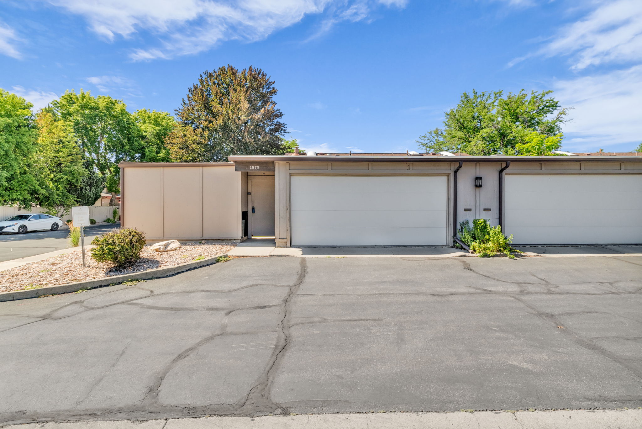 Contemporary exterior with a tan facade and white garage doors