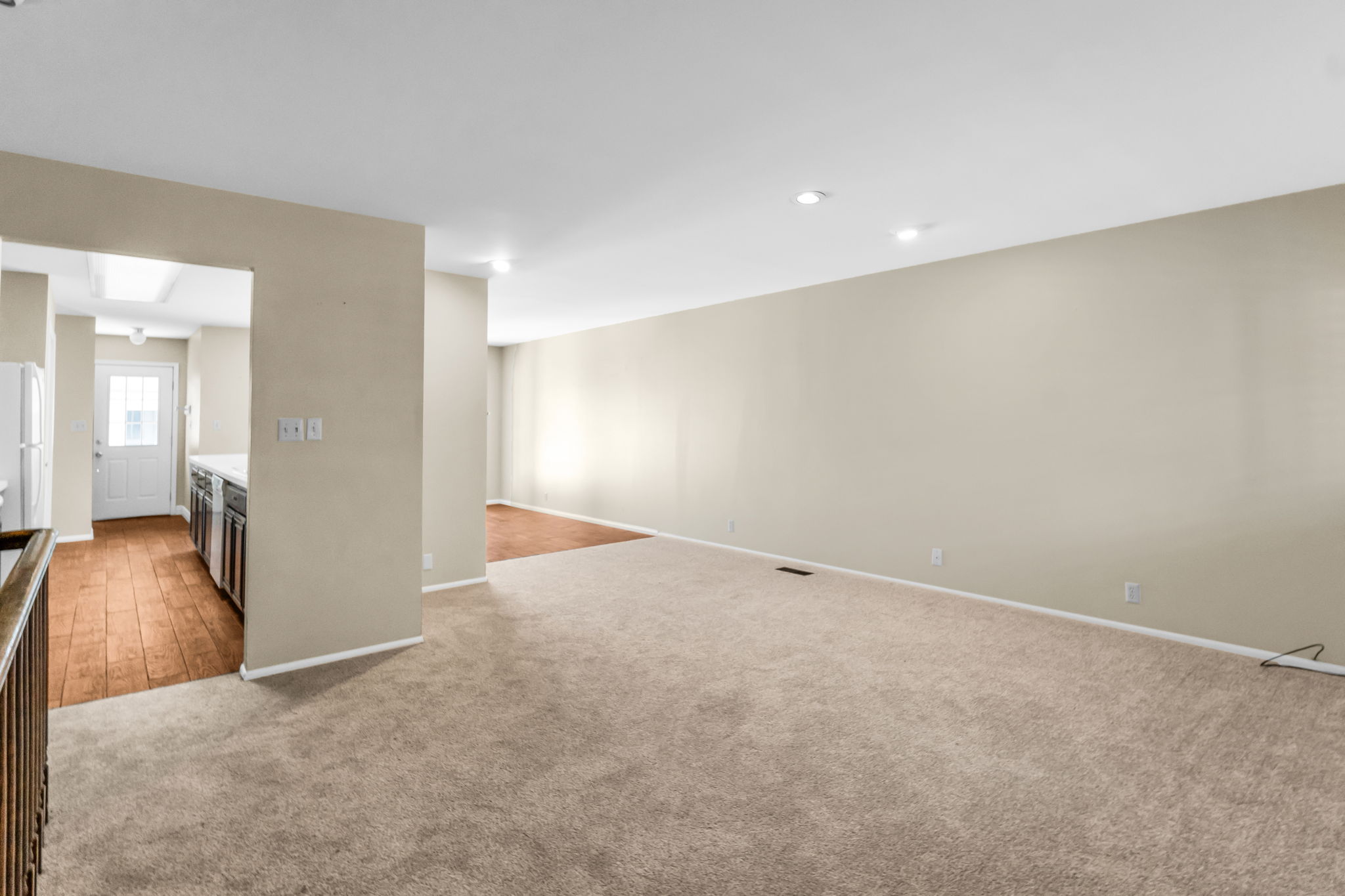 Open-concept living area with neutral carpeting and recessed lighting