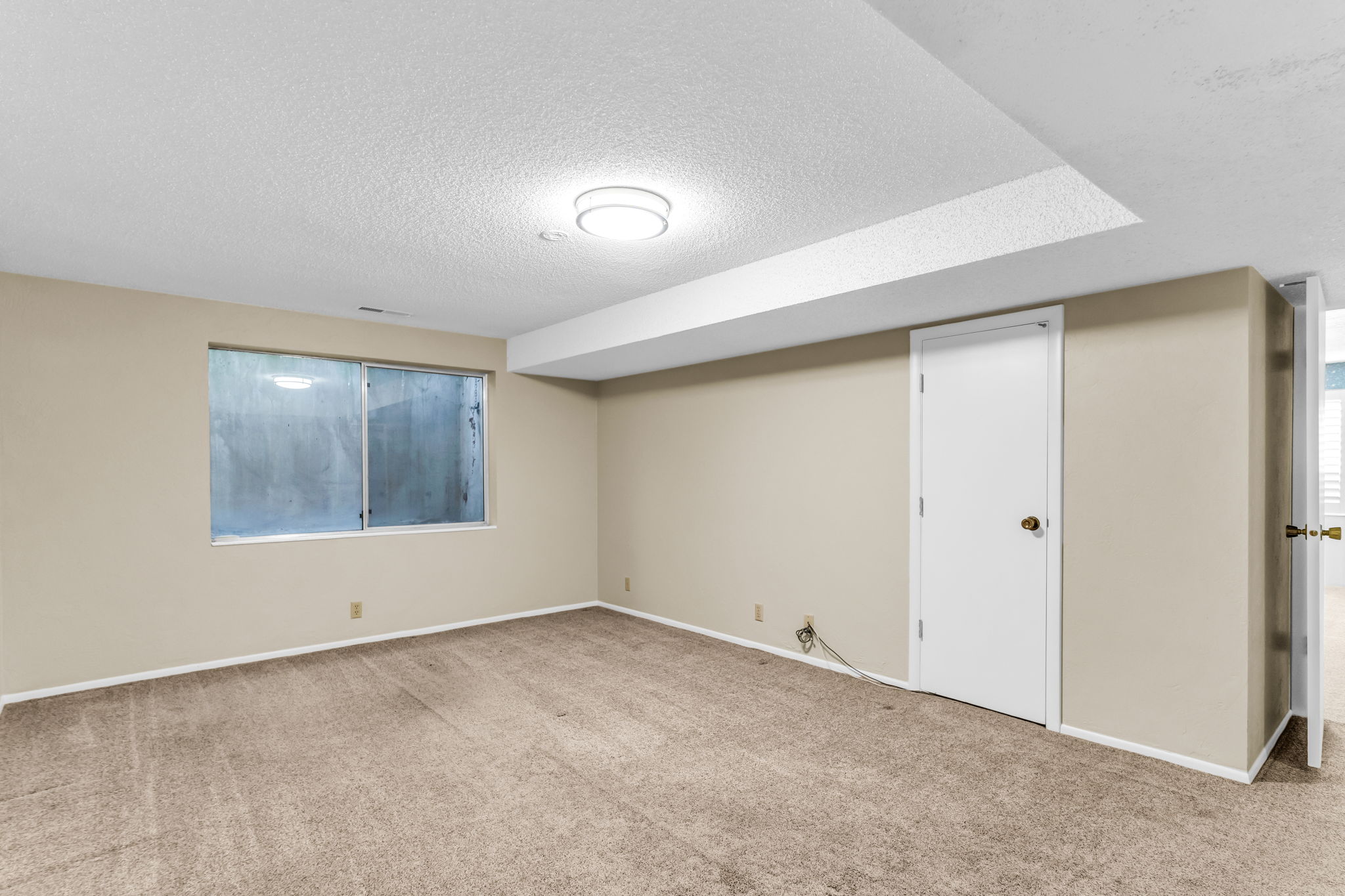 Carpeted room featuring a large window, neutral wall paint, white trim, and a flush-mount ceiling light