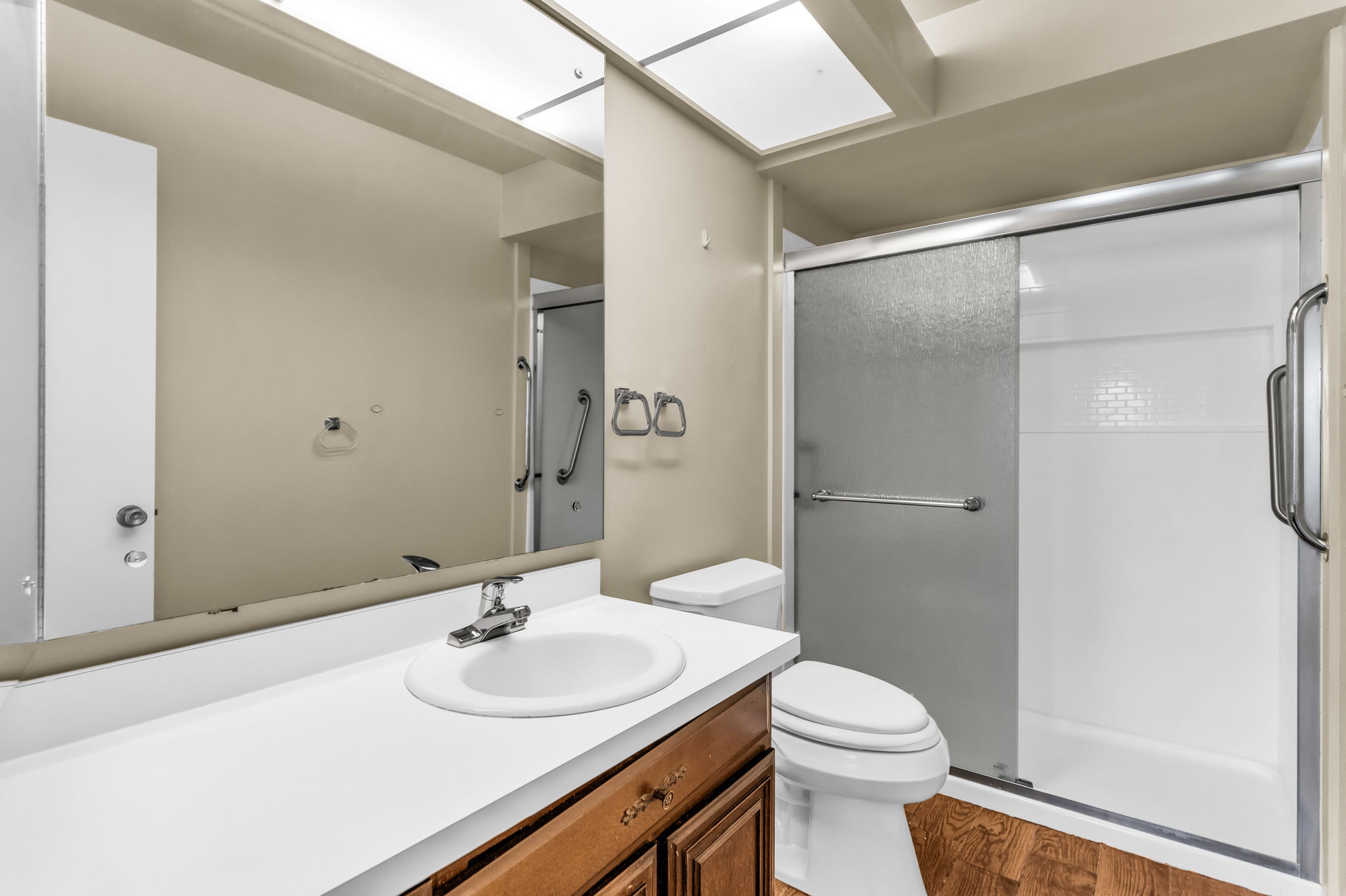 Full bathroom featuring a single vanity with a white countertop and wood-finish cabinetry