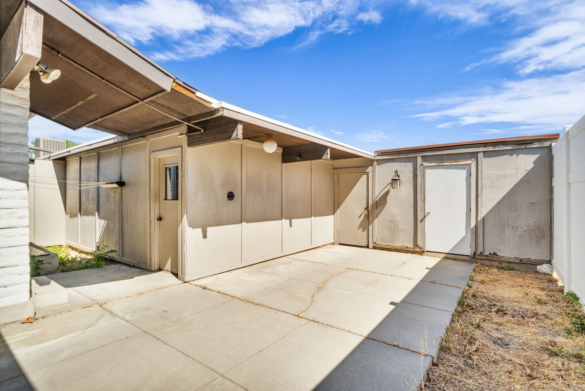 Concrete patio area featuring a covered overhang and exterior wall sconces