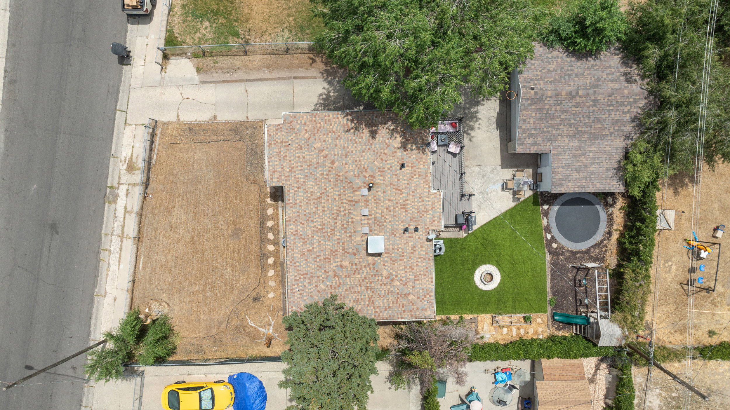 Rear exterior featuring a patio, artificial turf lawn, built-in fire pit, and in-ground trampoline