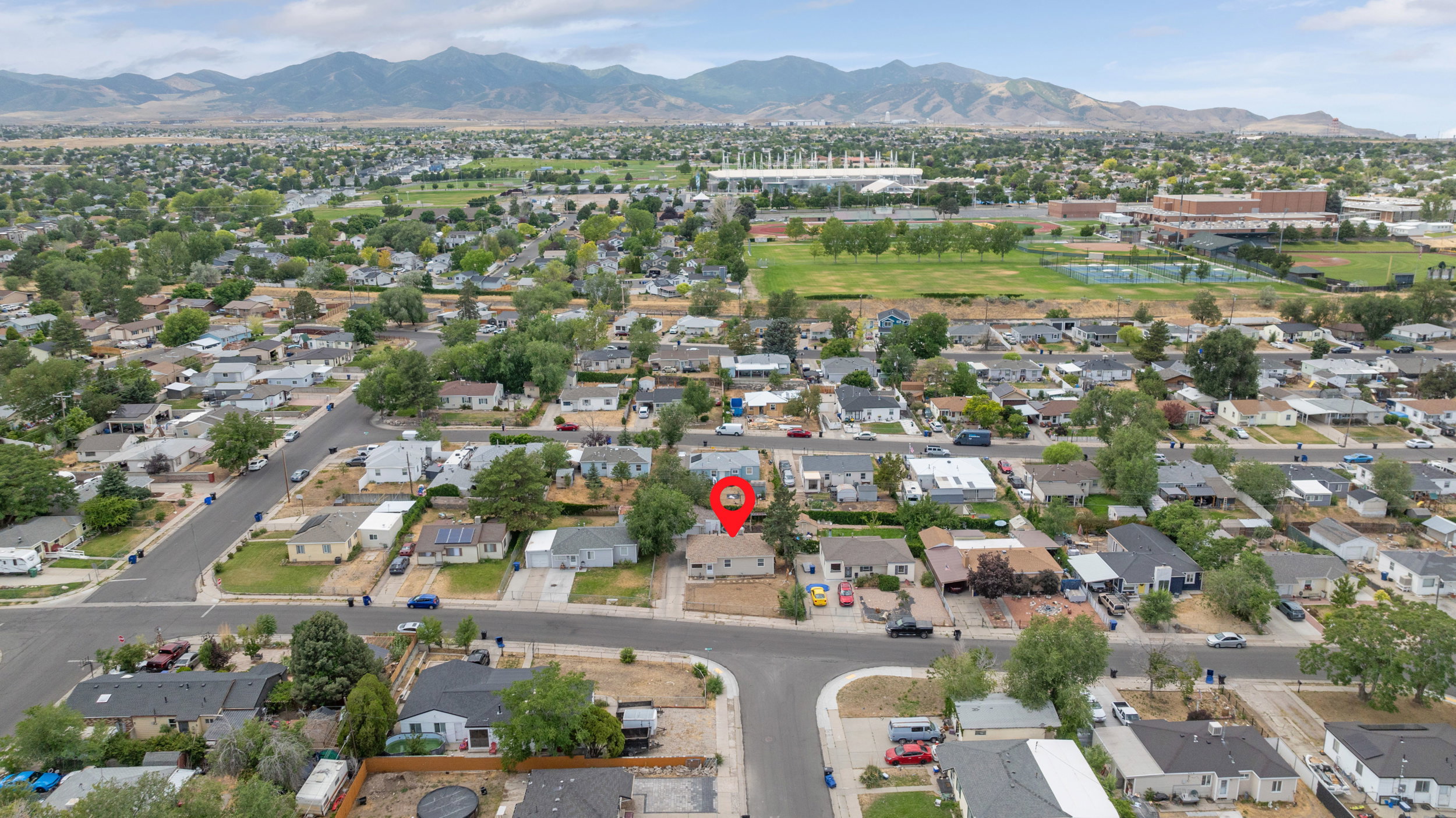 Aerial perspective of a residential neighborhood featuring single-story homes with mature trees and paved streets