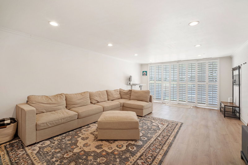 Spacious living room with beautiful LVP flooring ~ large, east facing windows that let in tons of natural light and plantation shutters.