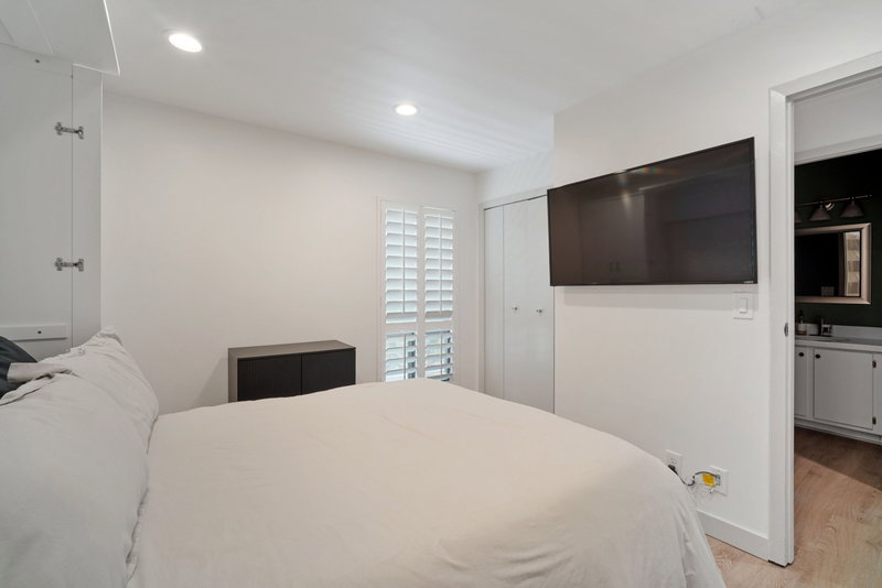Bedroom featuring recessed lighting, plantation shutters, and light wood-finish flooring extending into the visible bathroom