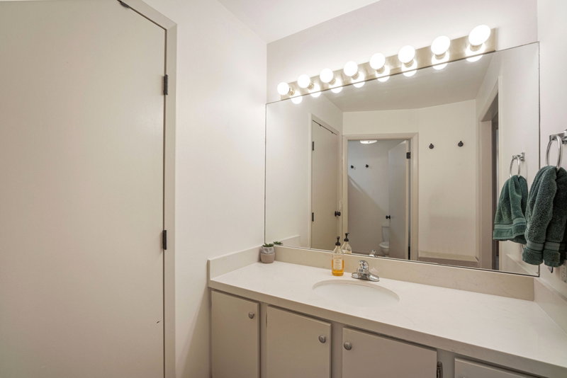 Bathroom vanity featuring an integrated sink, polished chrome faucet, and expansive wall-mounted mirror