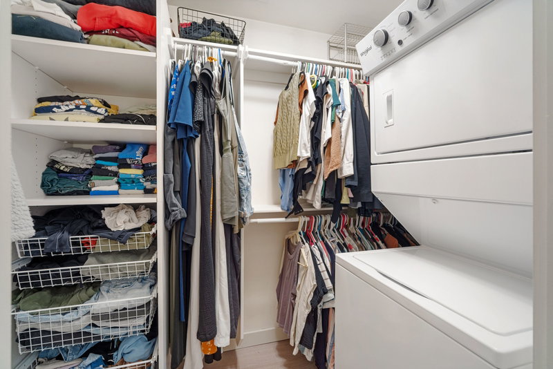 Laundry center with stacked washer and dryer unit, ample hanging storage, multiple shelving units, and pull-out wire baskets