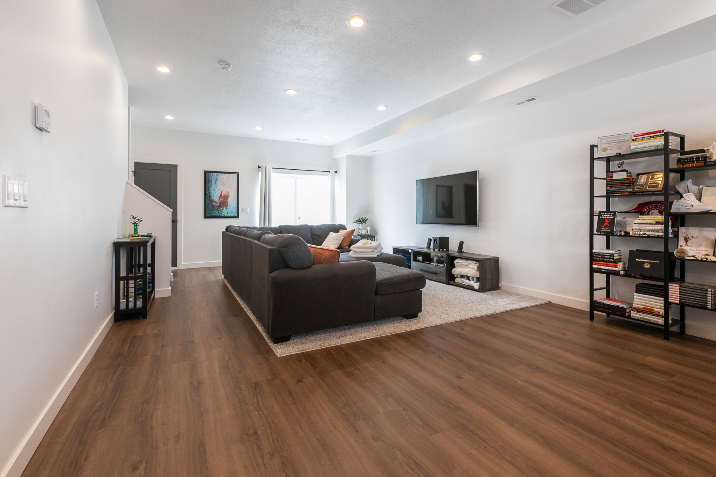 Spacious living area featuring wood-finish flooring, recessed lighting, and a large sliding glass door