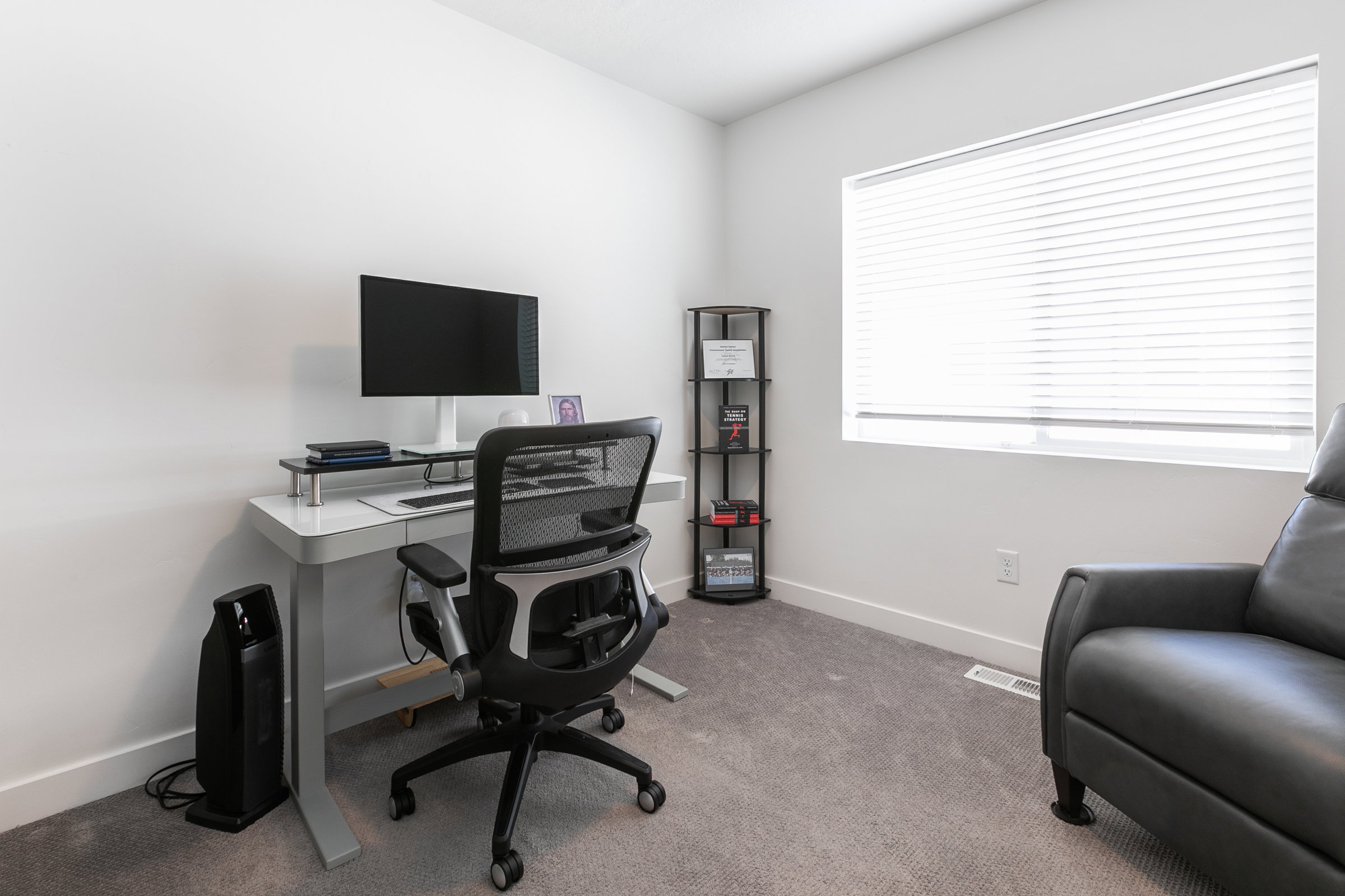 Bright room featuring a large window with horizontal blinds, neutral wall paint, and gray carpet flooring