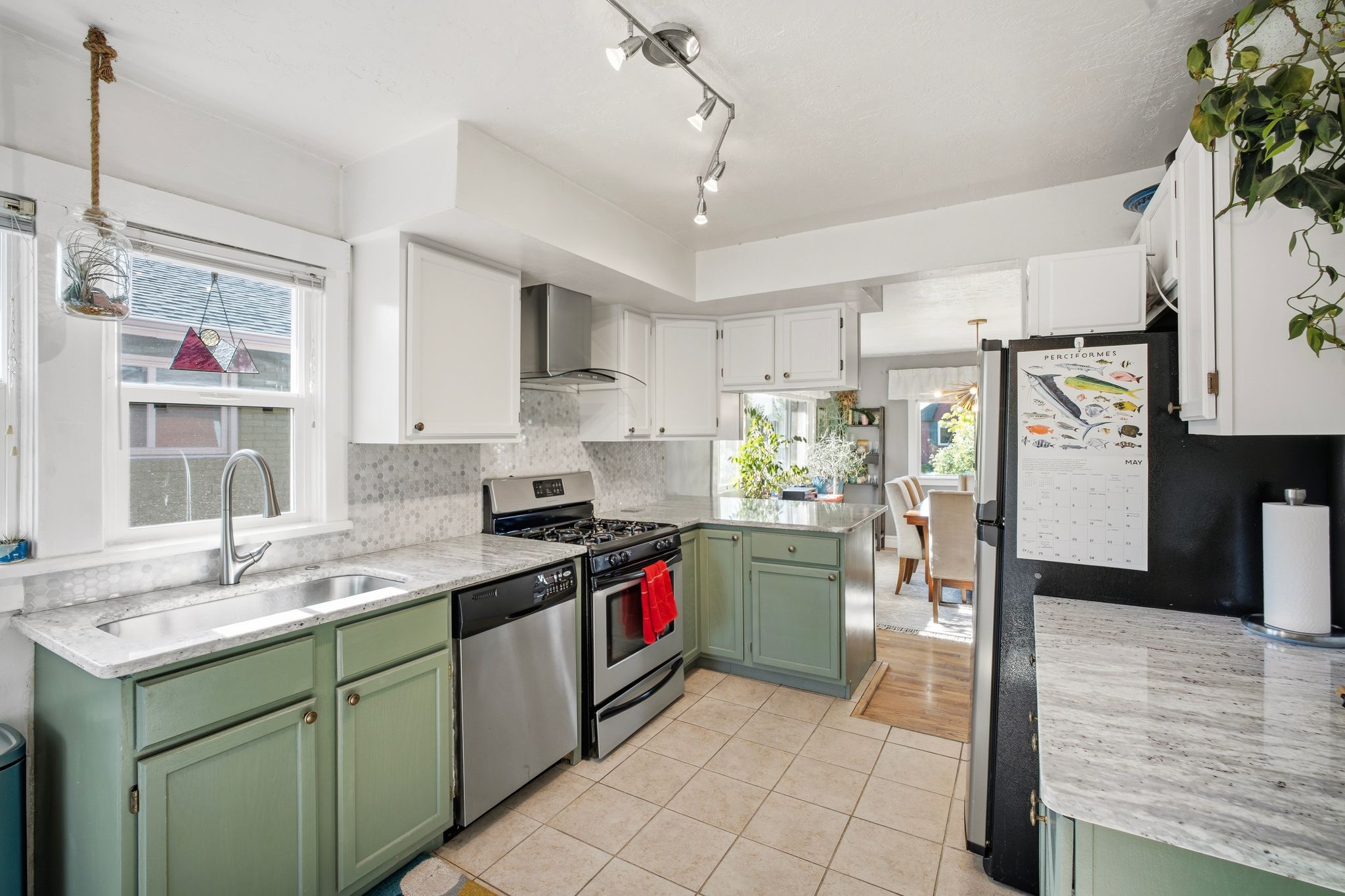 Kitchen featuring light green and white cabinetry, stone countertops, stainless steel appliances, and a tiled floor