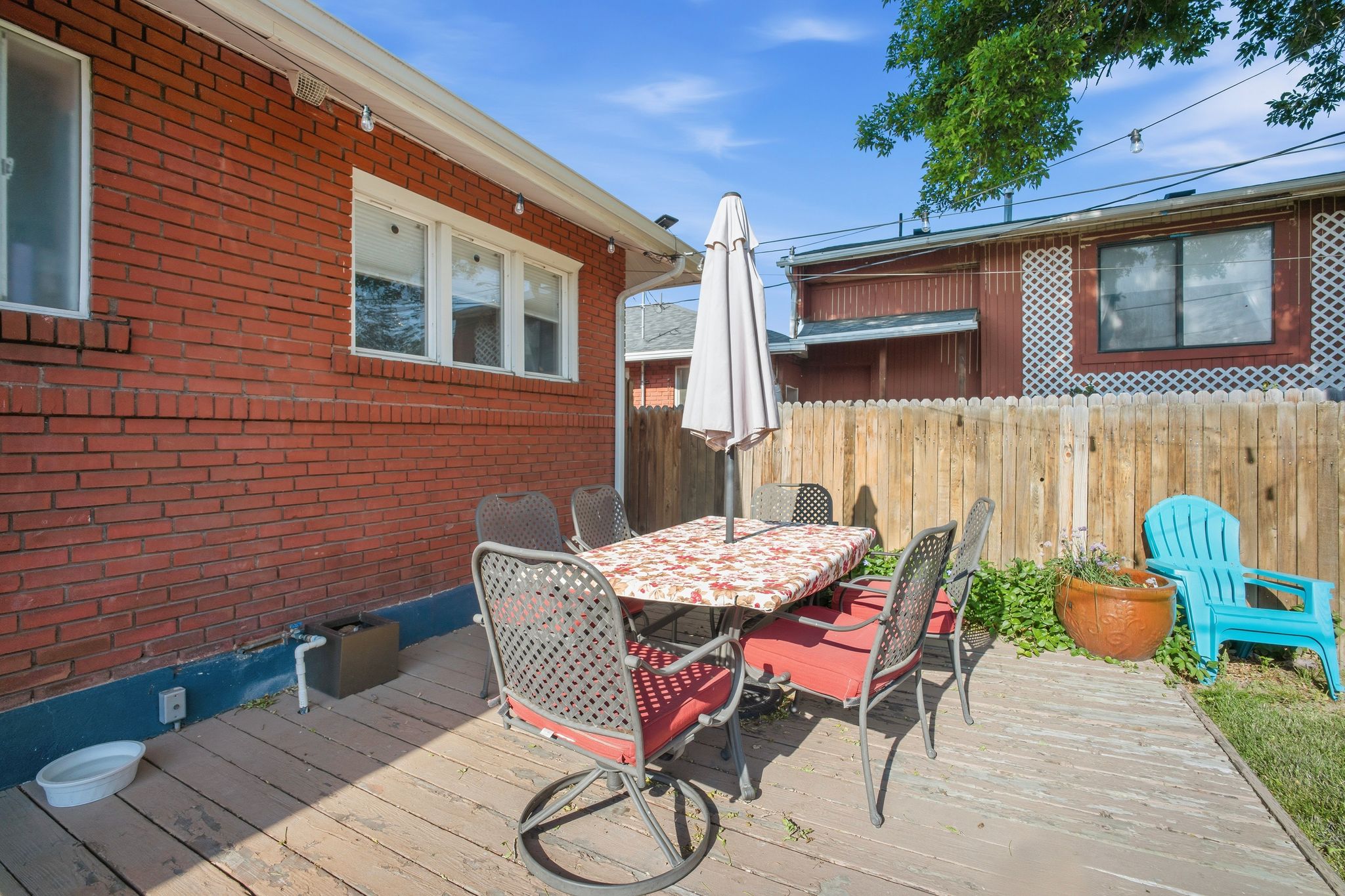 Wood deck patio with a red brick exterior, white trim windows, and a wooden privacy fence