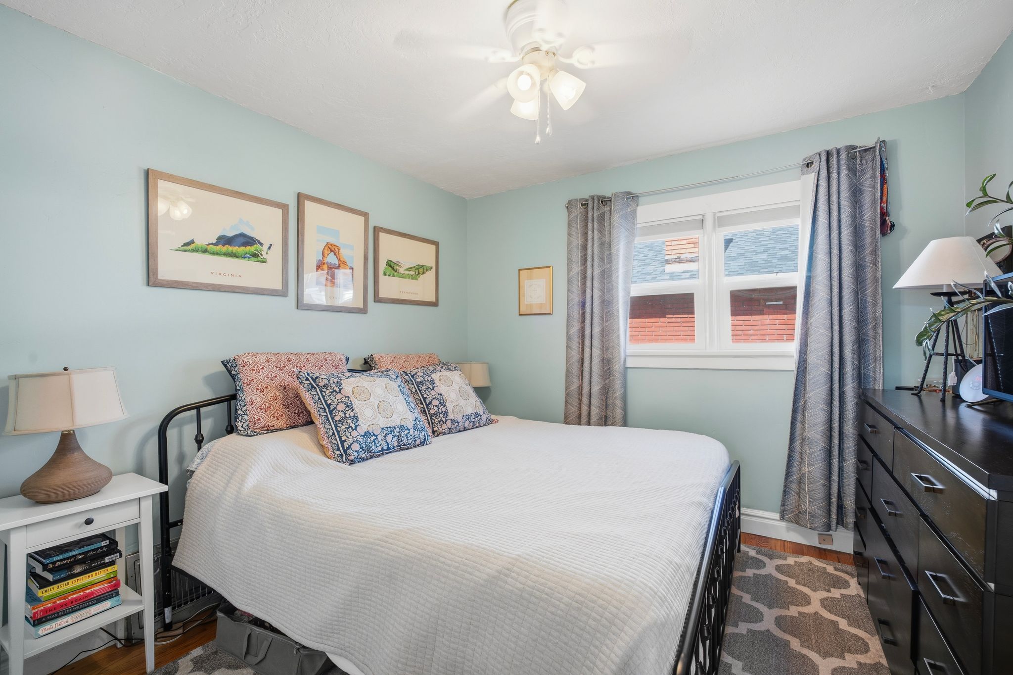 Bedroom featuring light blue walls, a white ceiling fan, and hardwood flooring