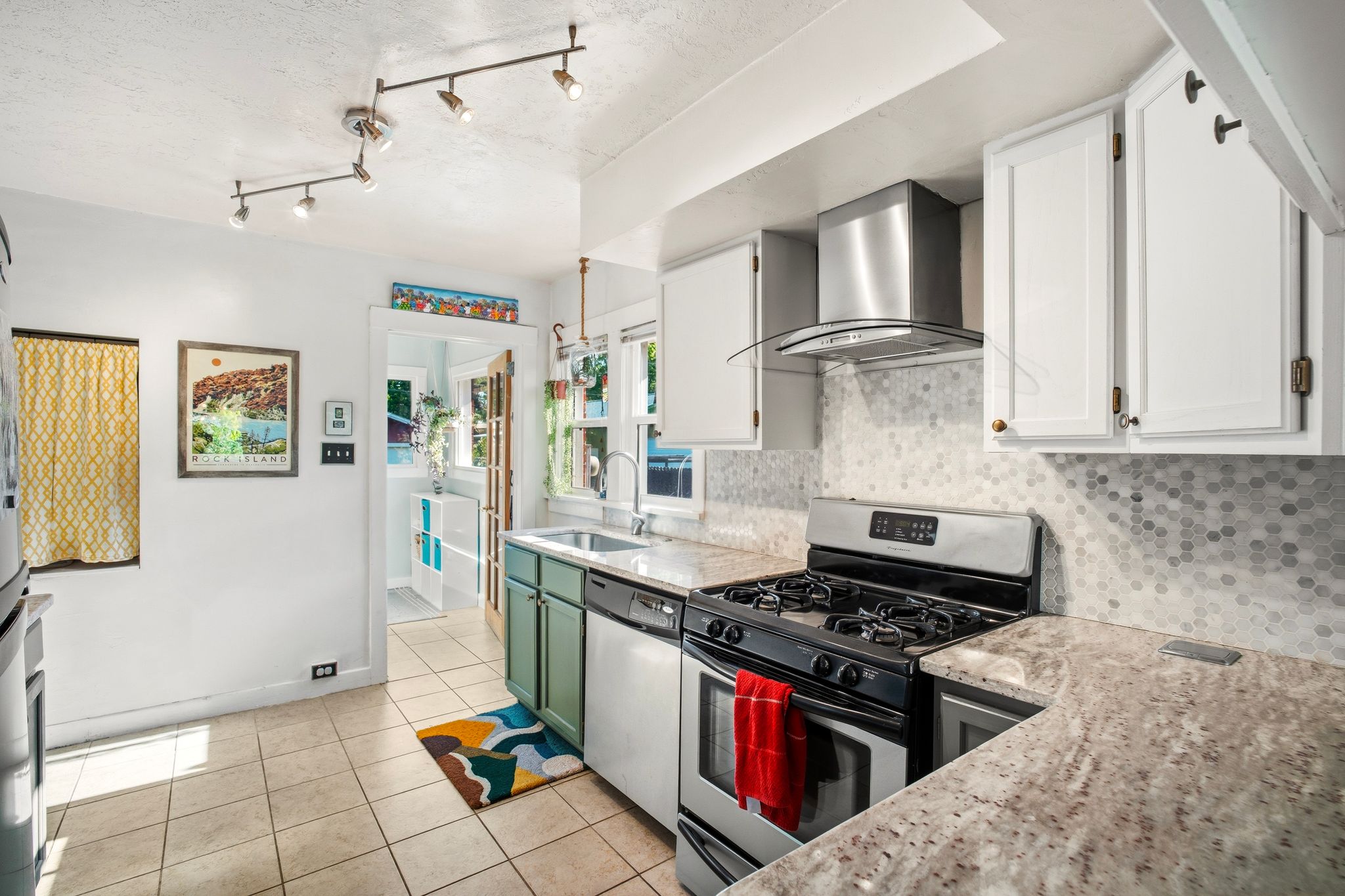 Kitchen featuring white upper cabinetry, teal lower cabinetry, and light-colored countertops
