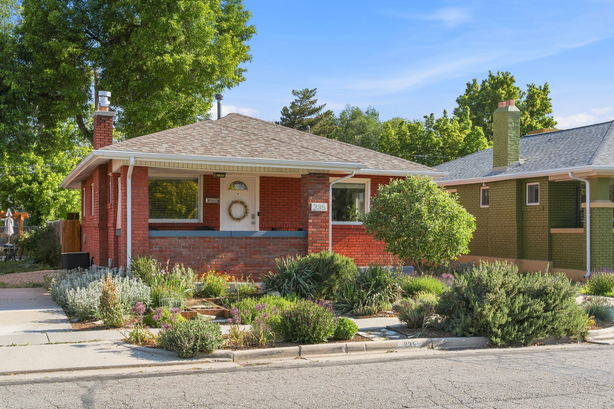 Red brick exterior featuring a covered front porch, a full-lite entry door with decorative glass, and a shingle roof