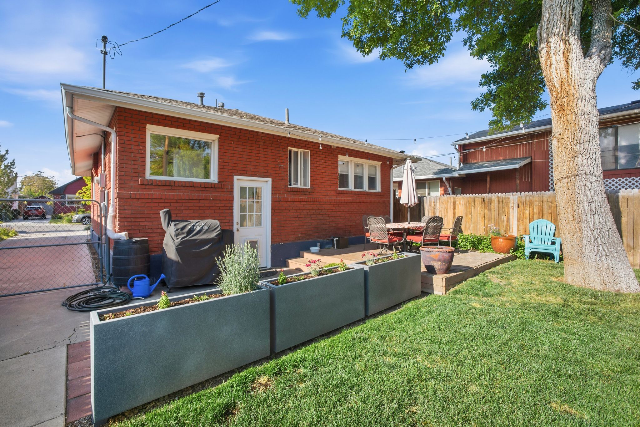 Expansive backyard featuring a lush lawn, mature tree, and a concrete patio