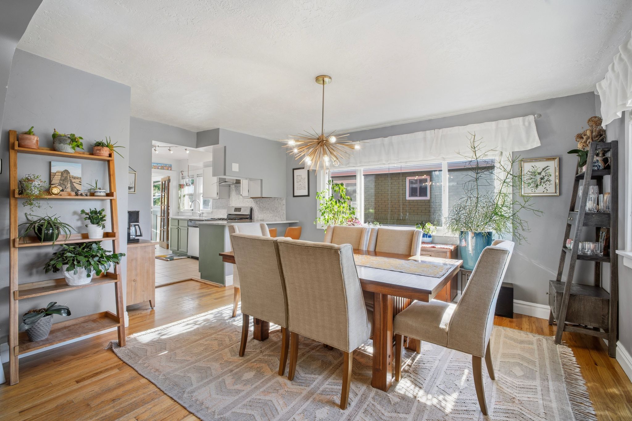 Hardwood flooring throughout the dining area, featuring a contemporary chandelier and expansive window