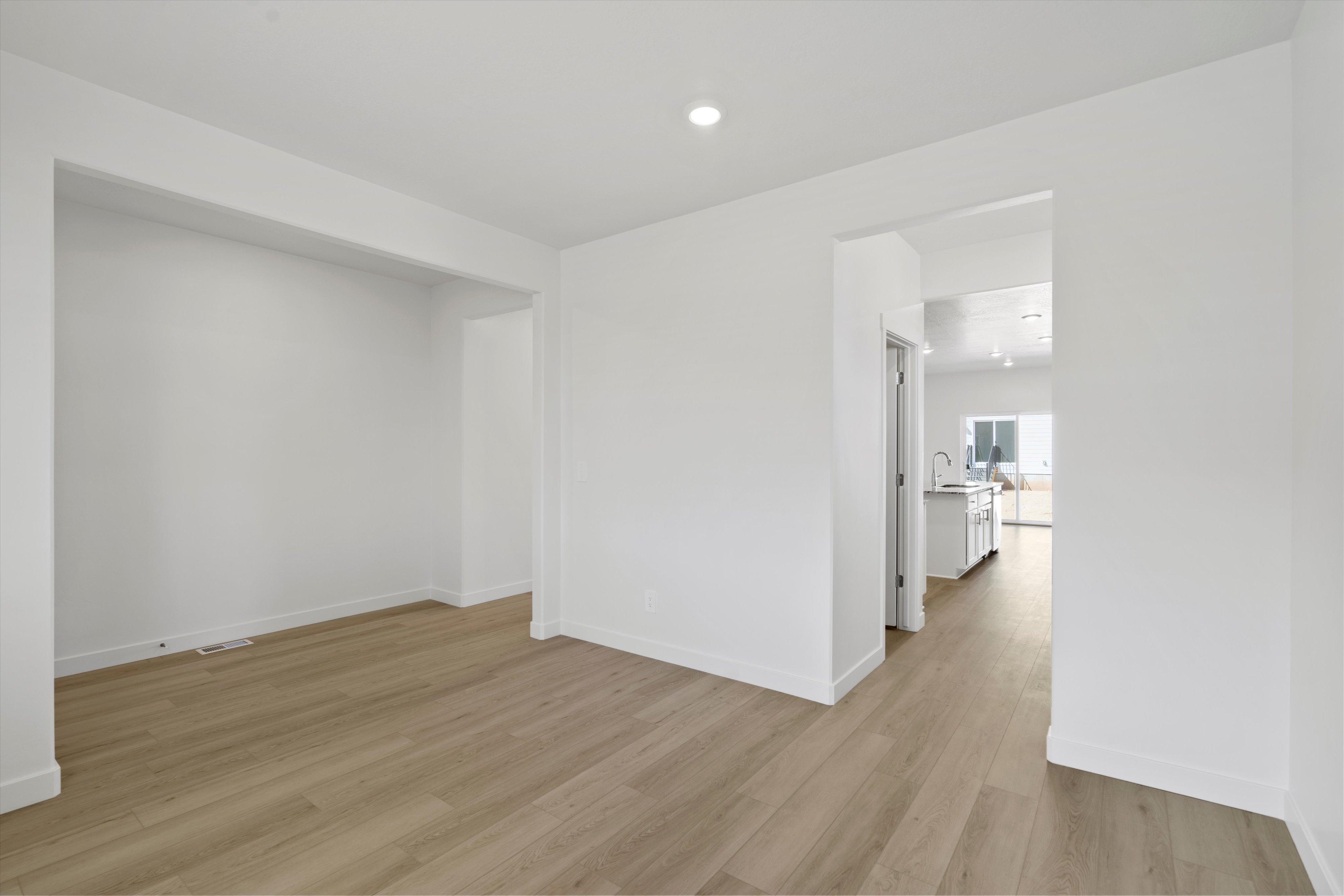 Spacious room featuring wood-finish flooring, white baseboards, and recessed lighting