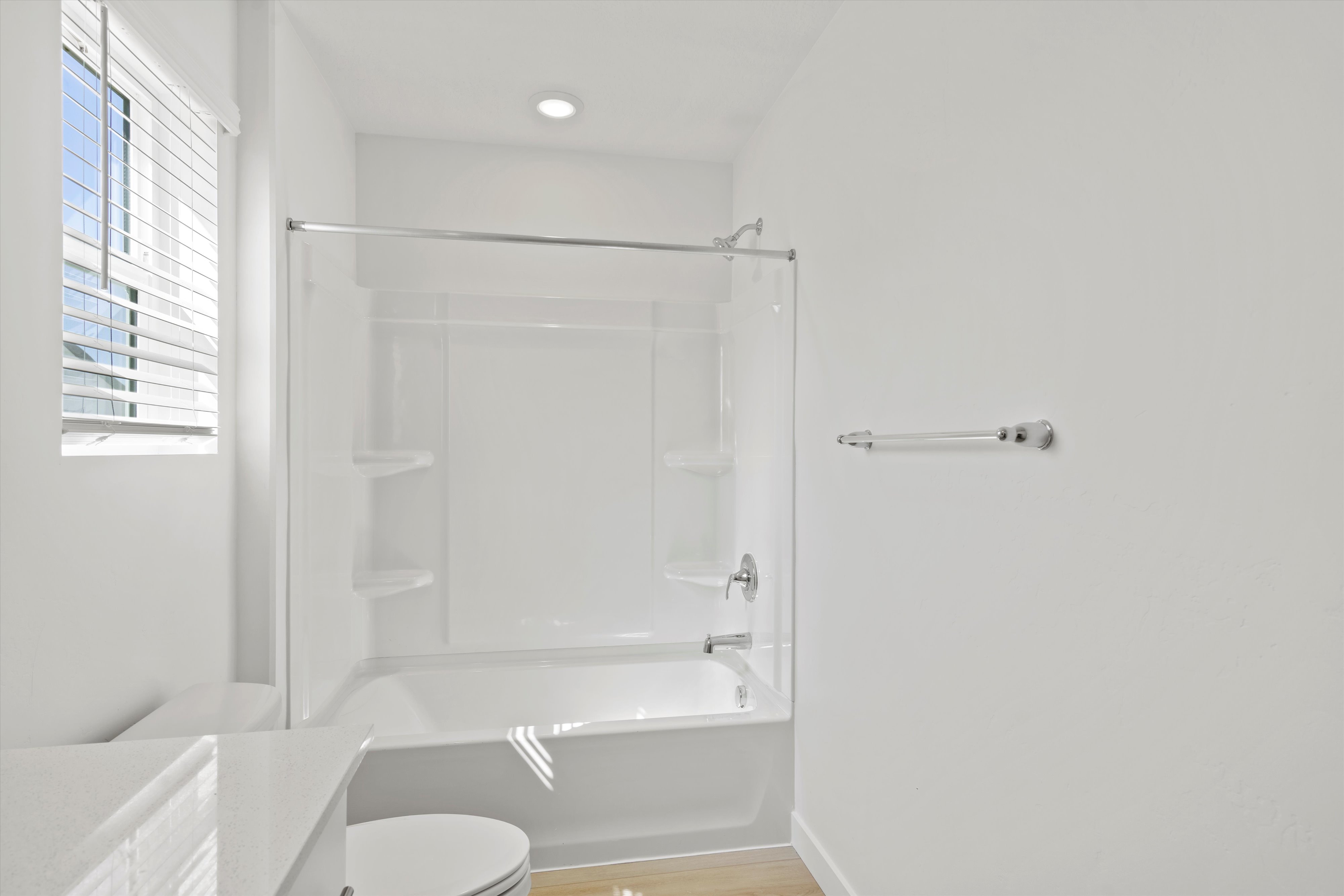 Bathroom featuring a white bathtub with an integrated shower, chrome fixtures, and a glass shower door