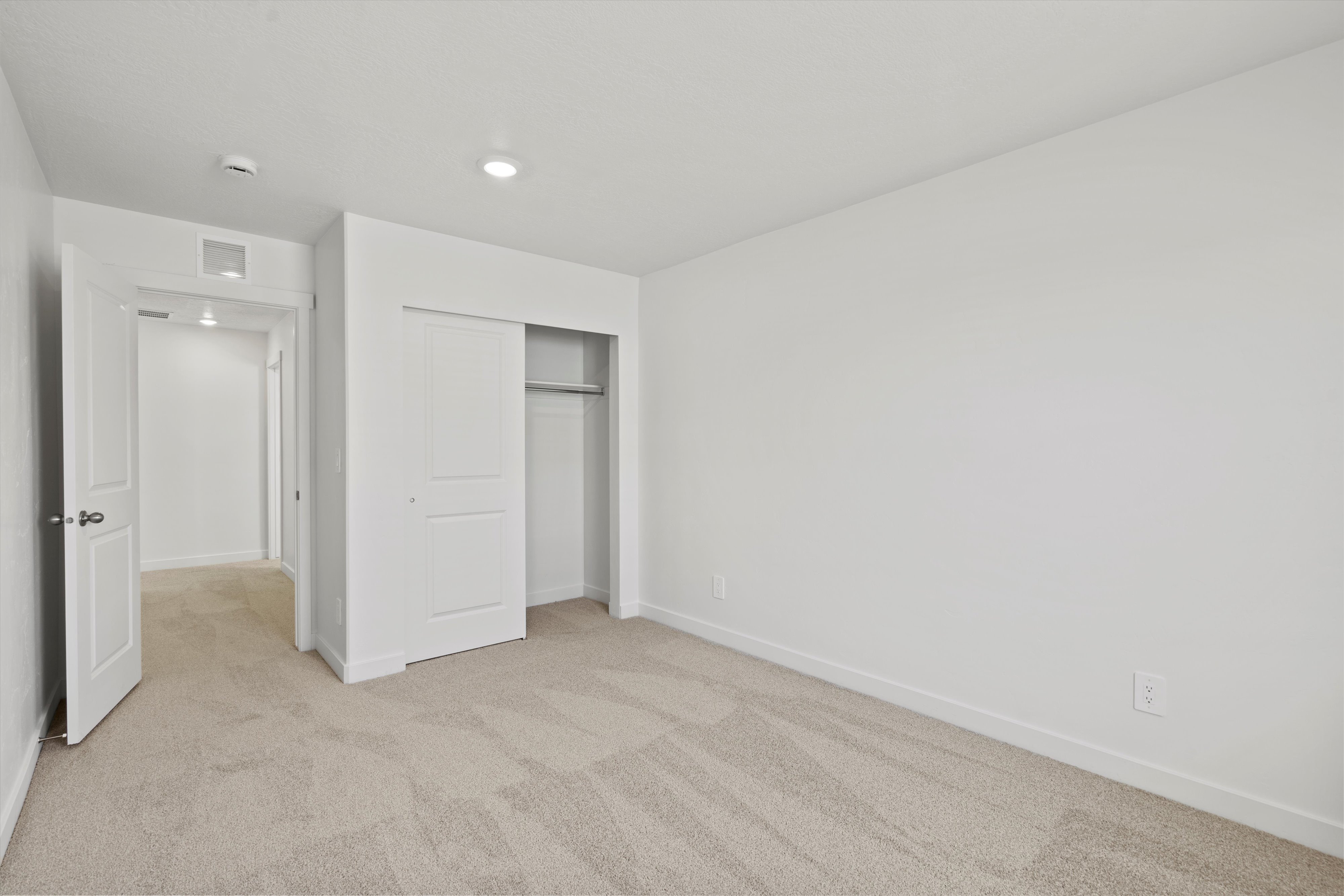 Spacious room featuring neutral carpeting, white walls, and a sliding closet door