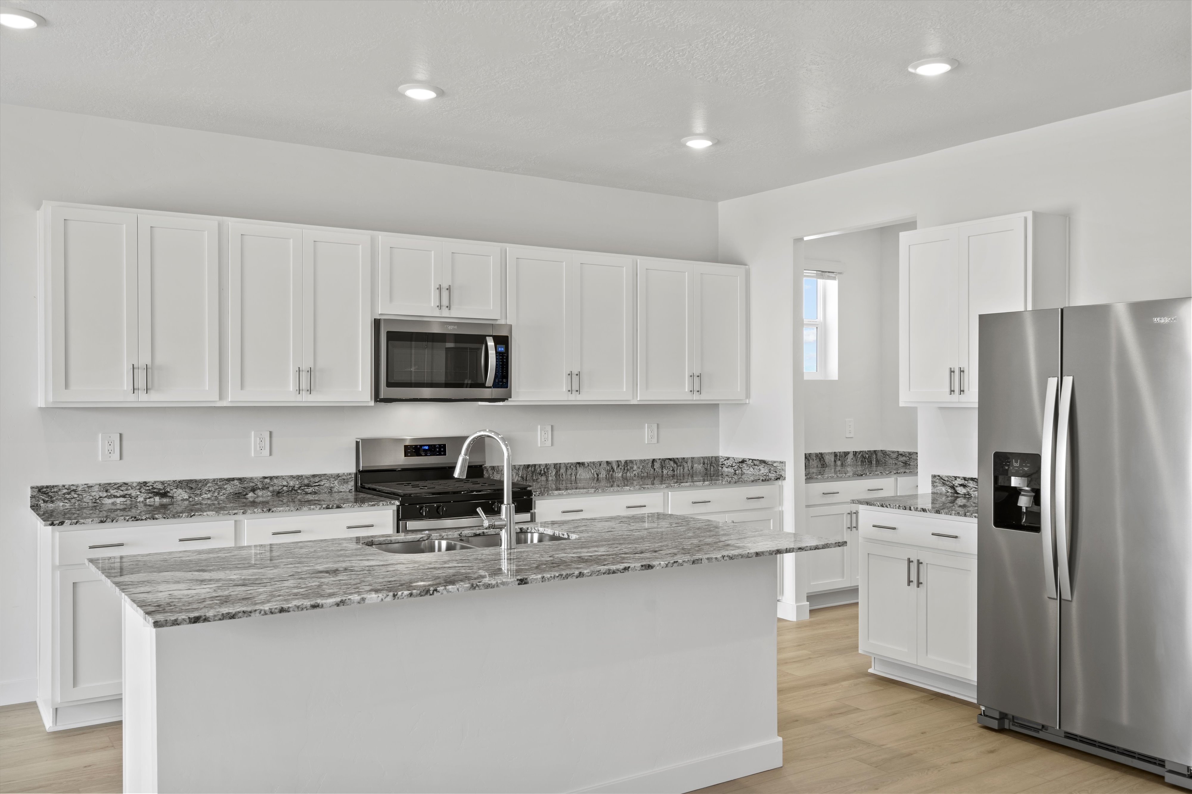 Kitchen featuring white shaker-style cabinetry, stainless steel appliances, granite countertops, and wood-finish flooring