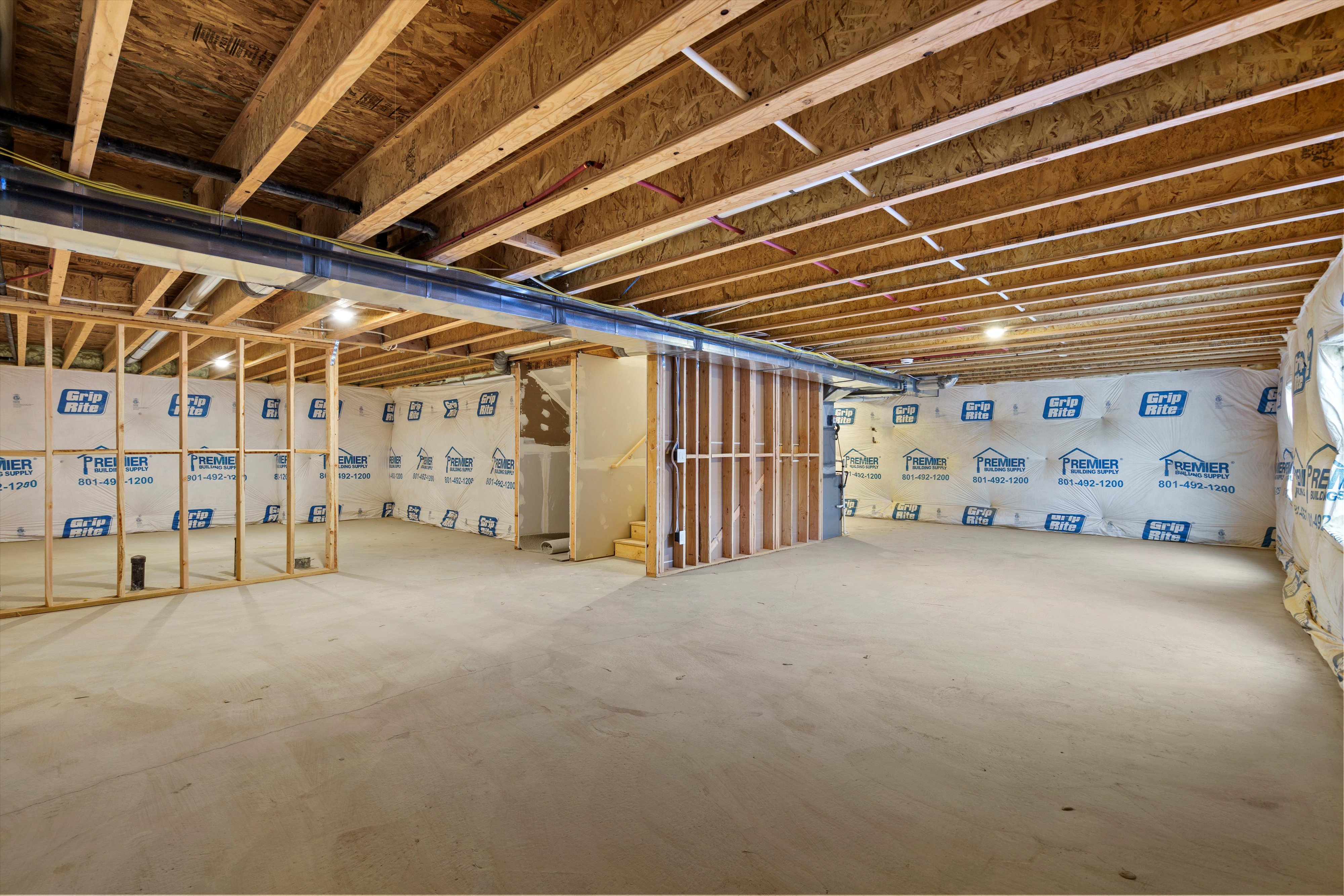 Expansive unfinished basement featuring concrete flooring and exposed ceiling joists