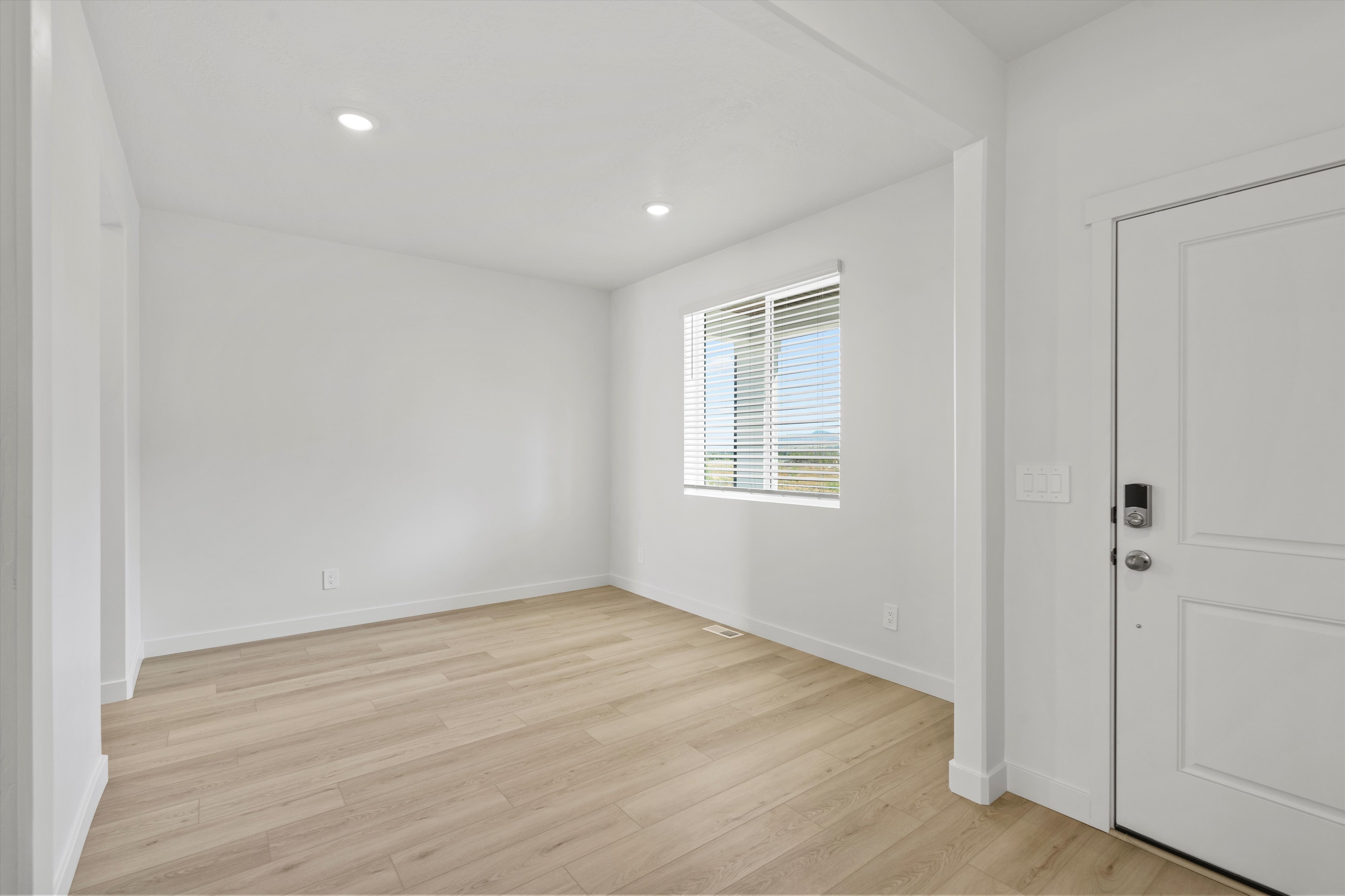 Entryway featuring light wood-finish flooring, recessed lighting, and a white paneled entry door with dark hardware