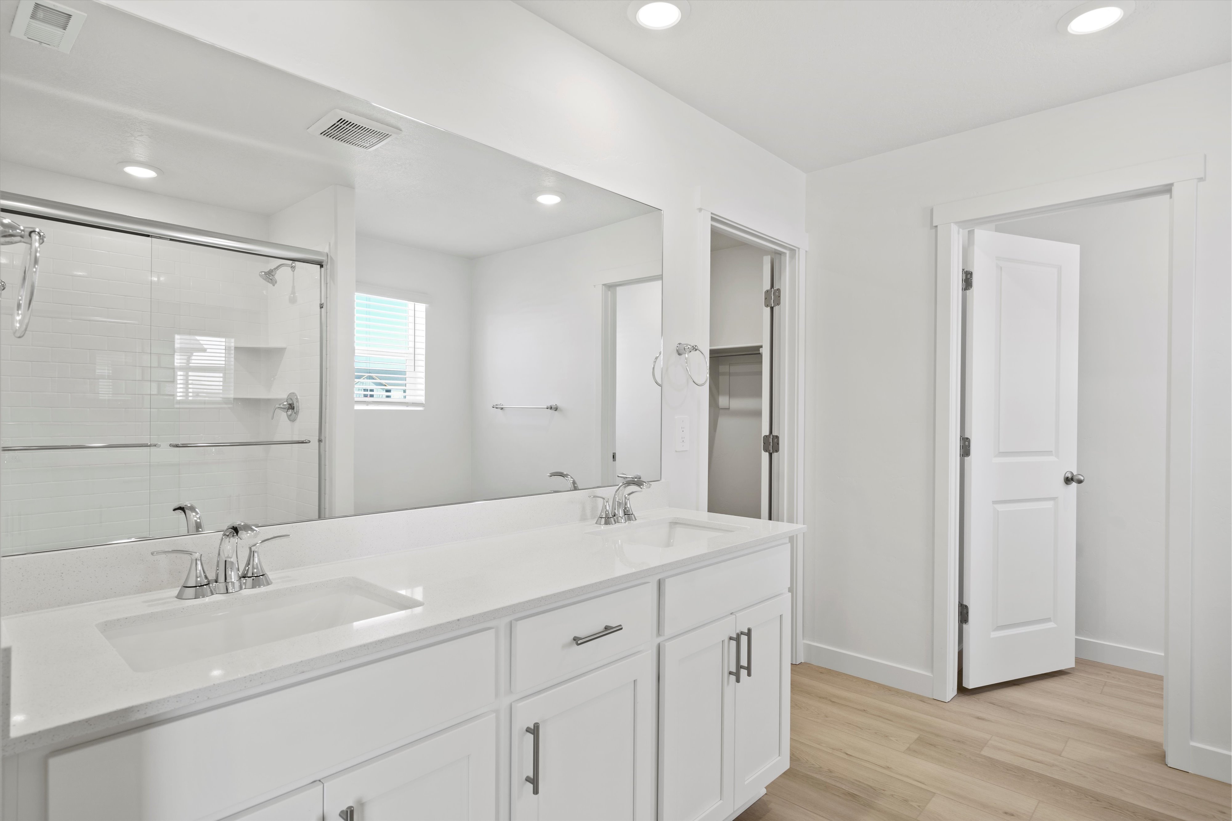 Double vanity with integrated sinks, white cabinetry, chrome fixtures, and a spacious framed mirror
