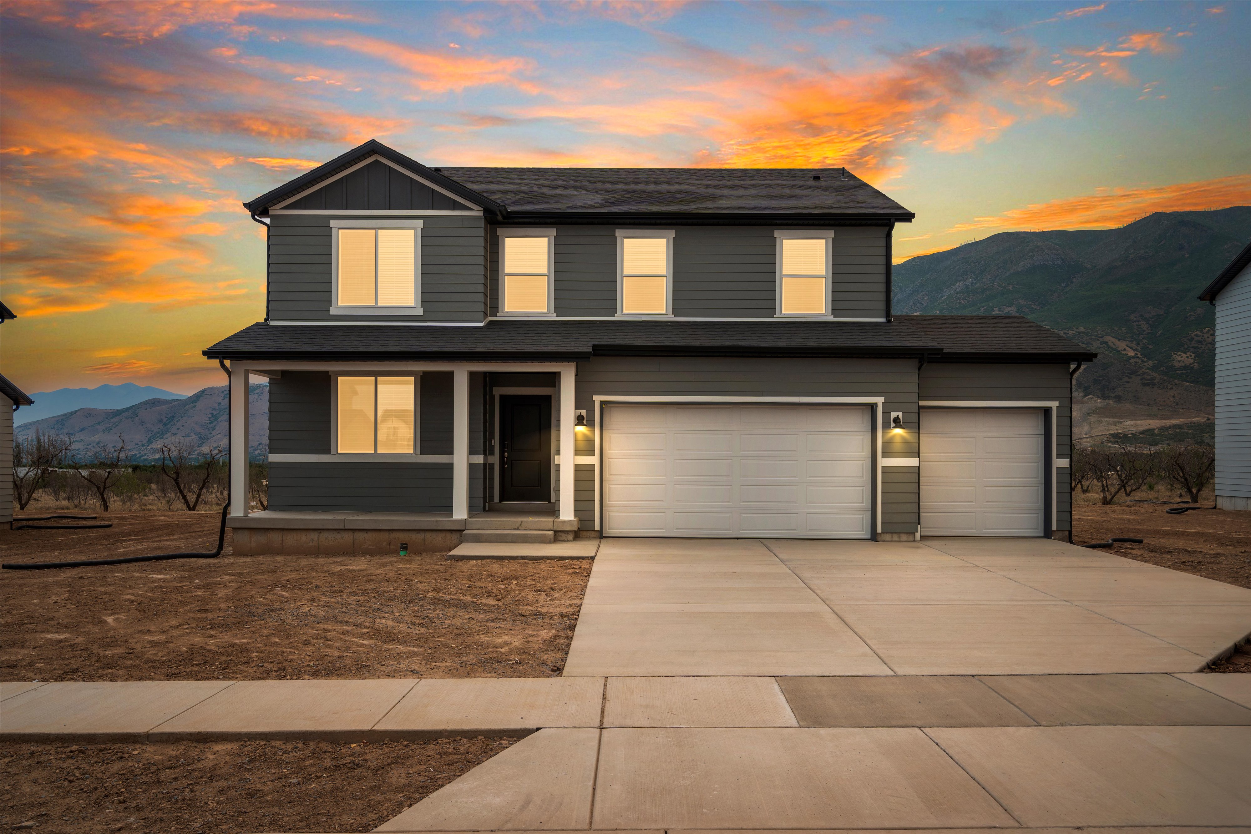 Contemporary two-story residence with dark gray siding, a covered front porch, and an attached two-car garage