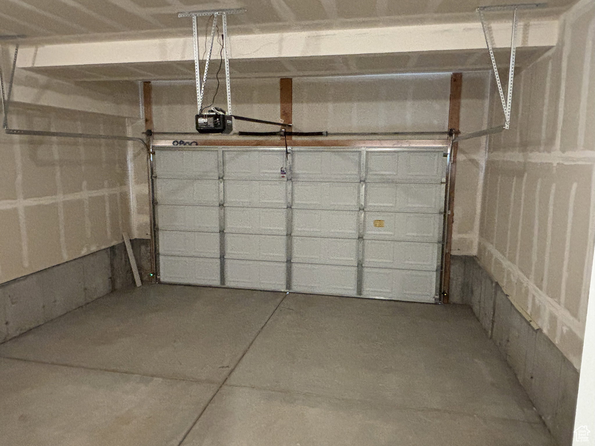 Spacious garage featuring a paneled overhead door, concrete flooring, and an automatic garage door opener system