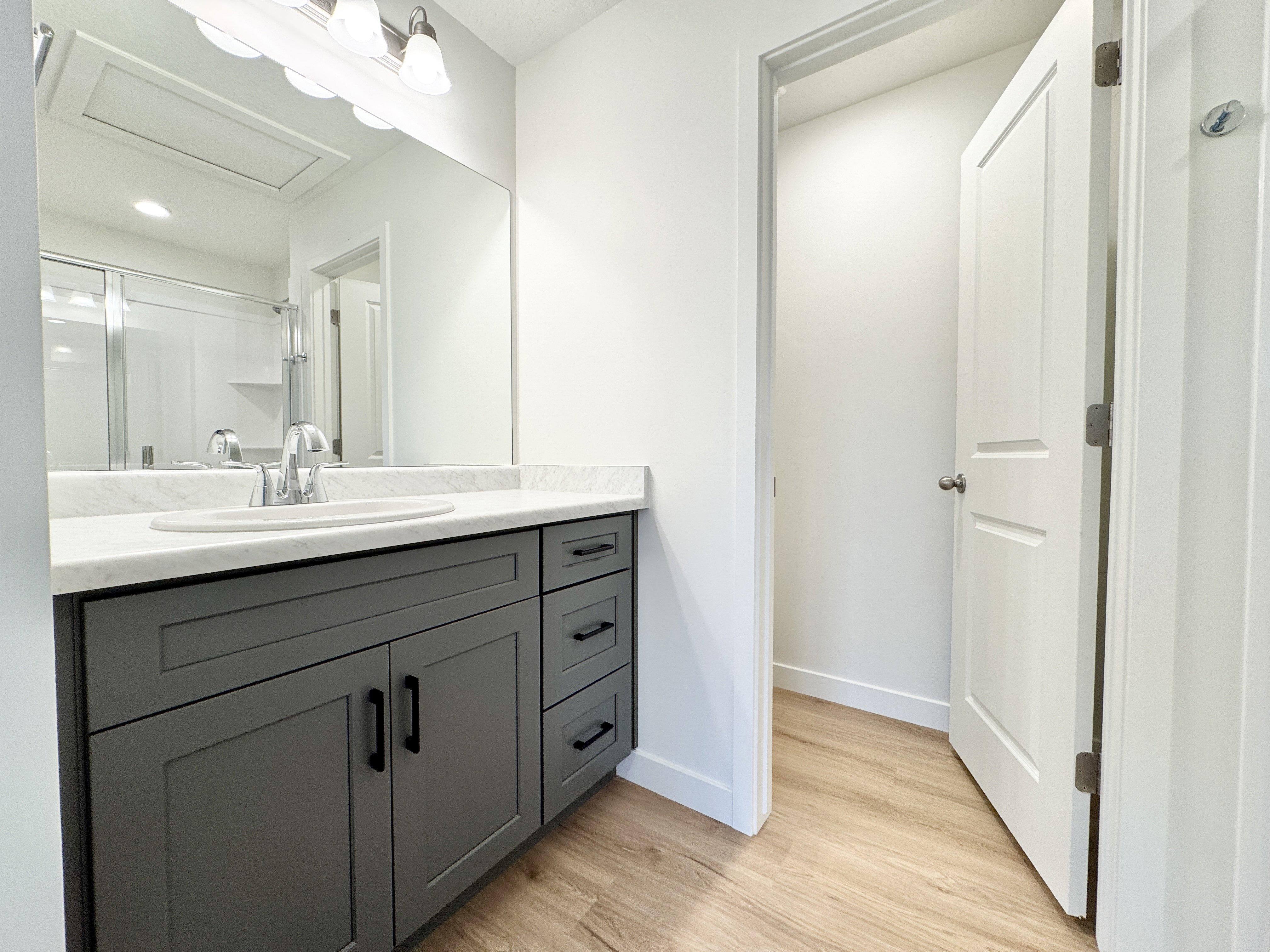 Bathroom featuring a dark gray vanity with black hardware, an integrated sink, and a light-toned countertop