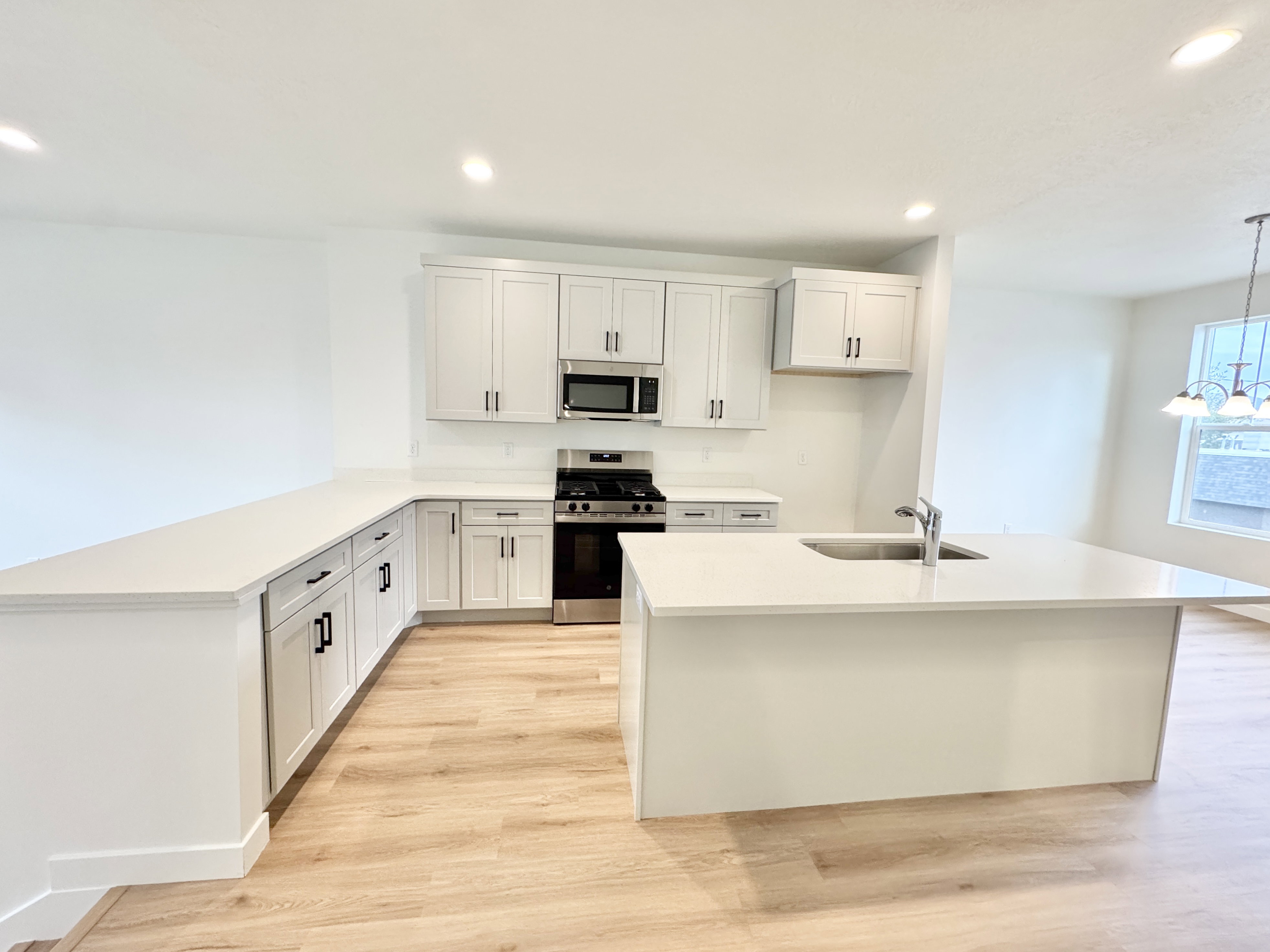 Modern kitchen featuring light wood-finish flooring, white cabinetry, and white countertops