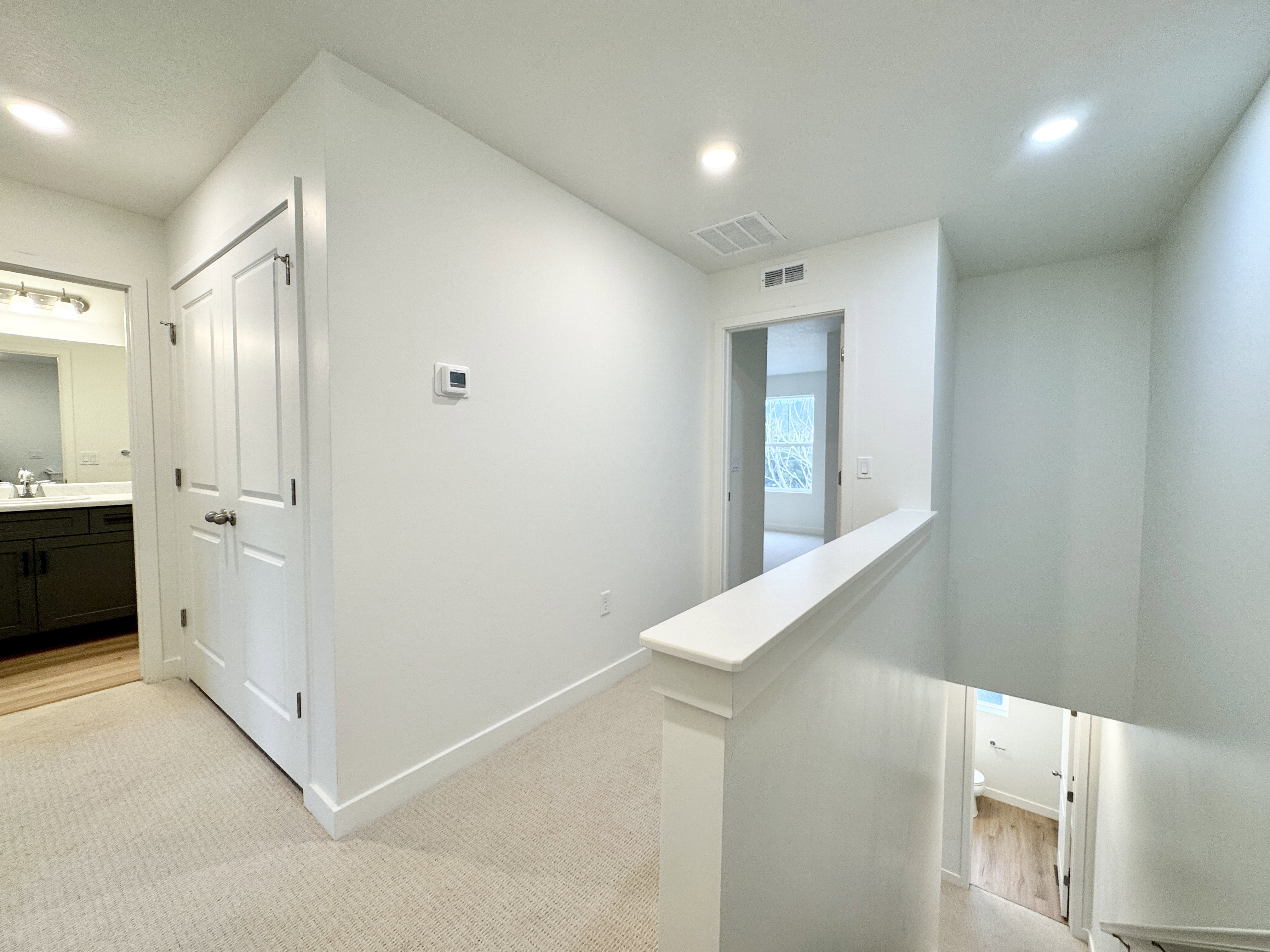 Upper-level hallway featuring neutral wall paint, recessed lighting, and carpet flooring