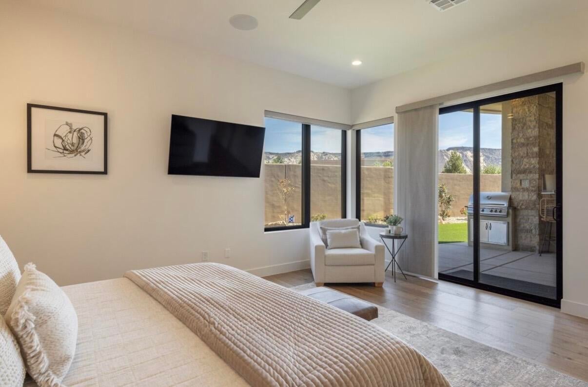 Spacious room featuring wood-finish flooring, large corner windows, and a sliding glass door providing direct outdoor access