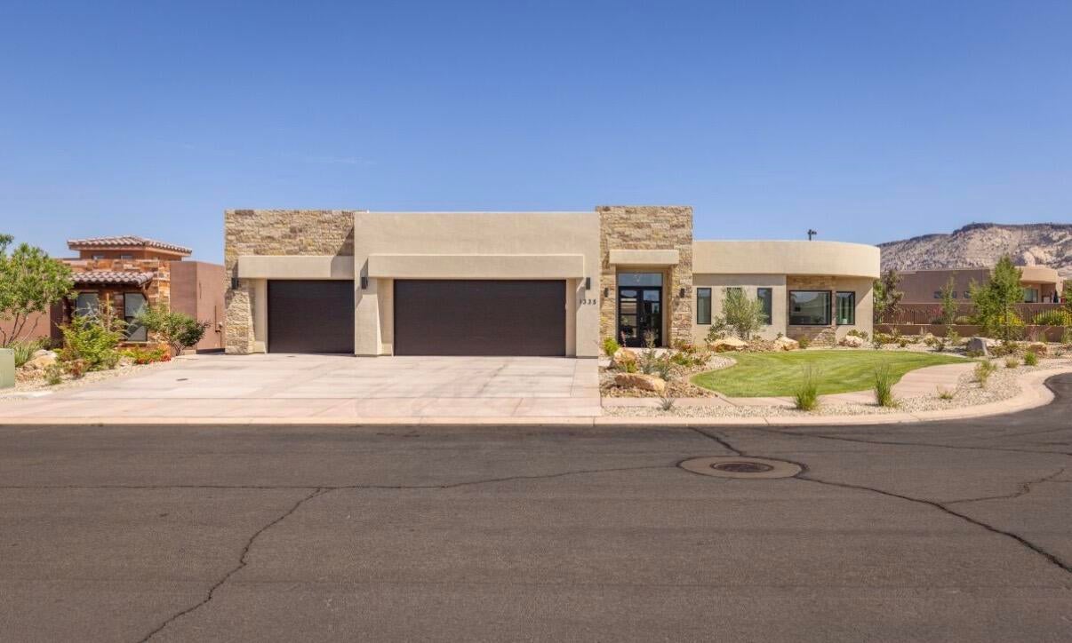 Contemporary stucco exterior featuring stone accents and a two-car garage