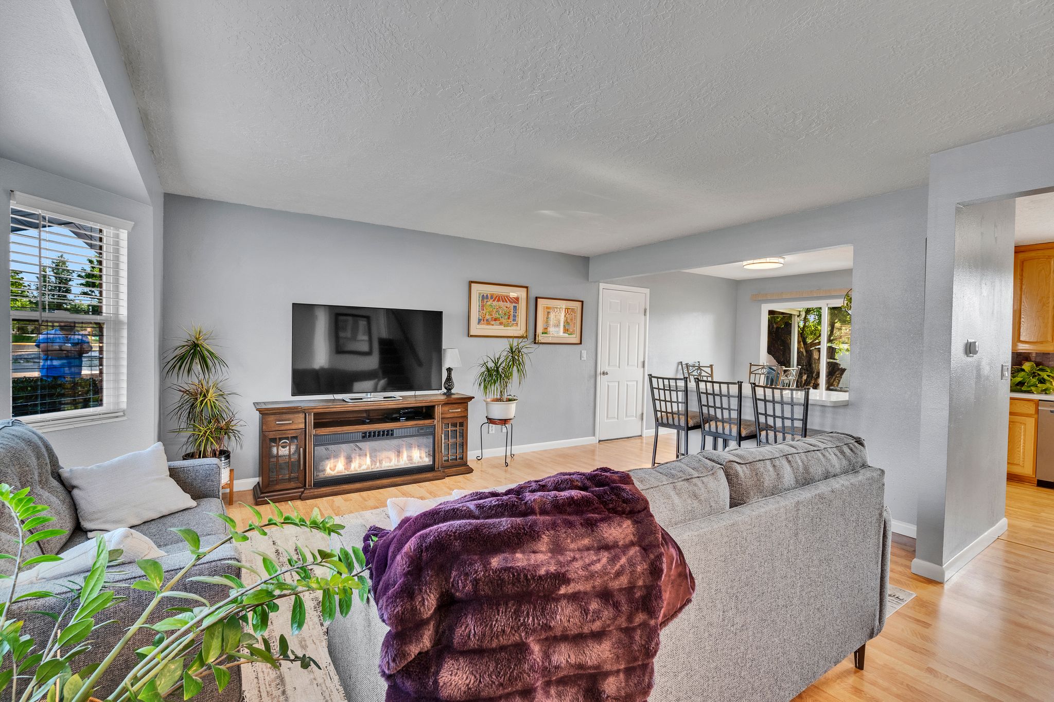 Living area featuring wood-finish flooring, light gray walls, and a recessed window with blinds