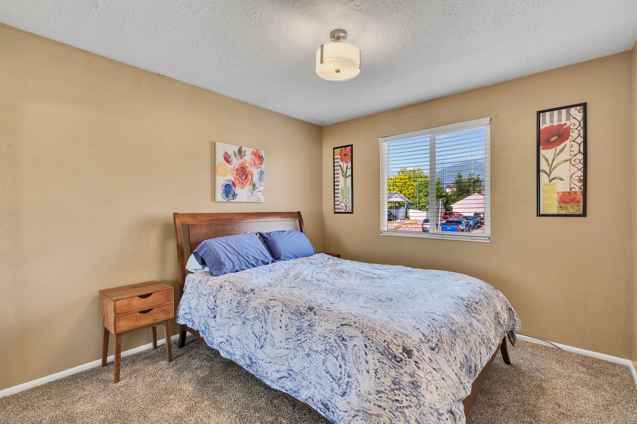 Bedroom featuring neutral-toned walls, textured carpeting, and a window with horizontal blinds
