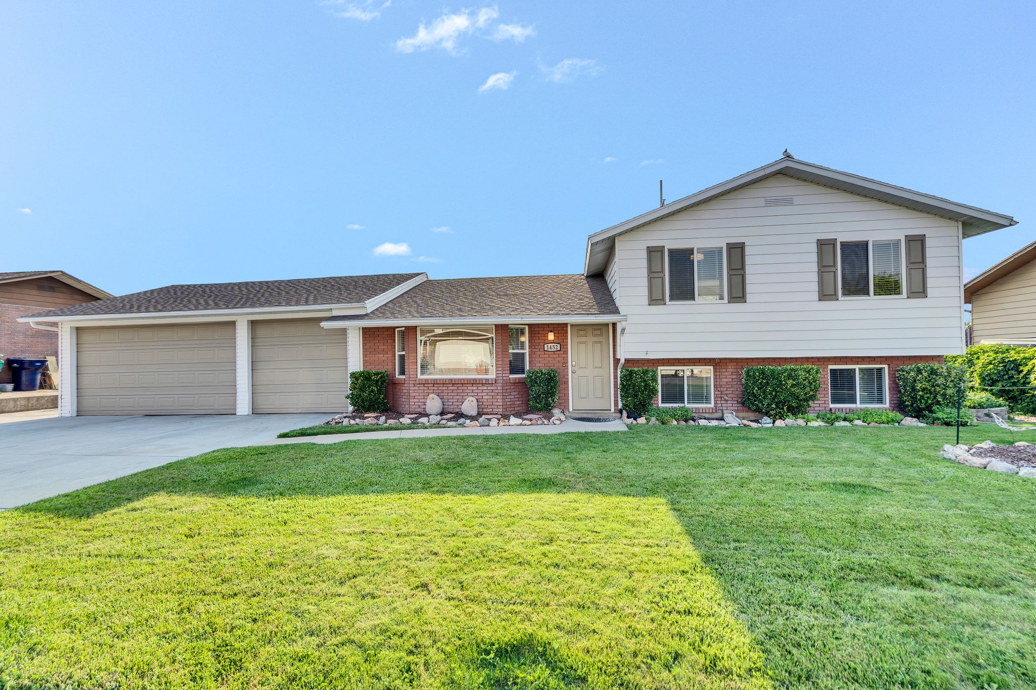 Split-level residence featuring a brick and siding exterior, a two-car garage, and a concrete driveway