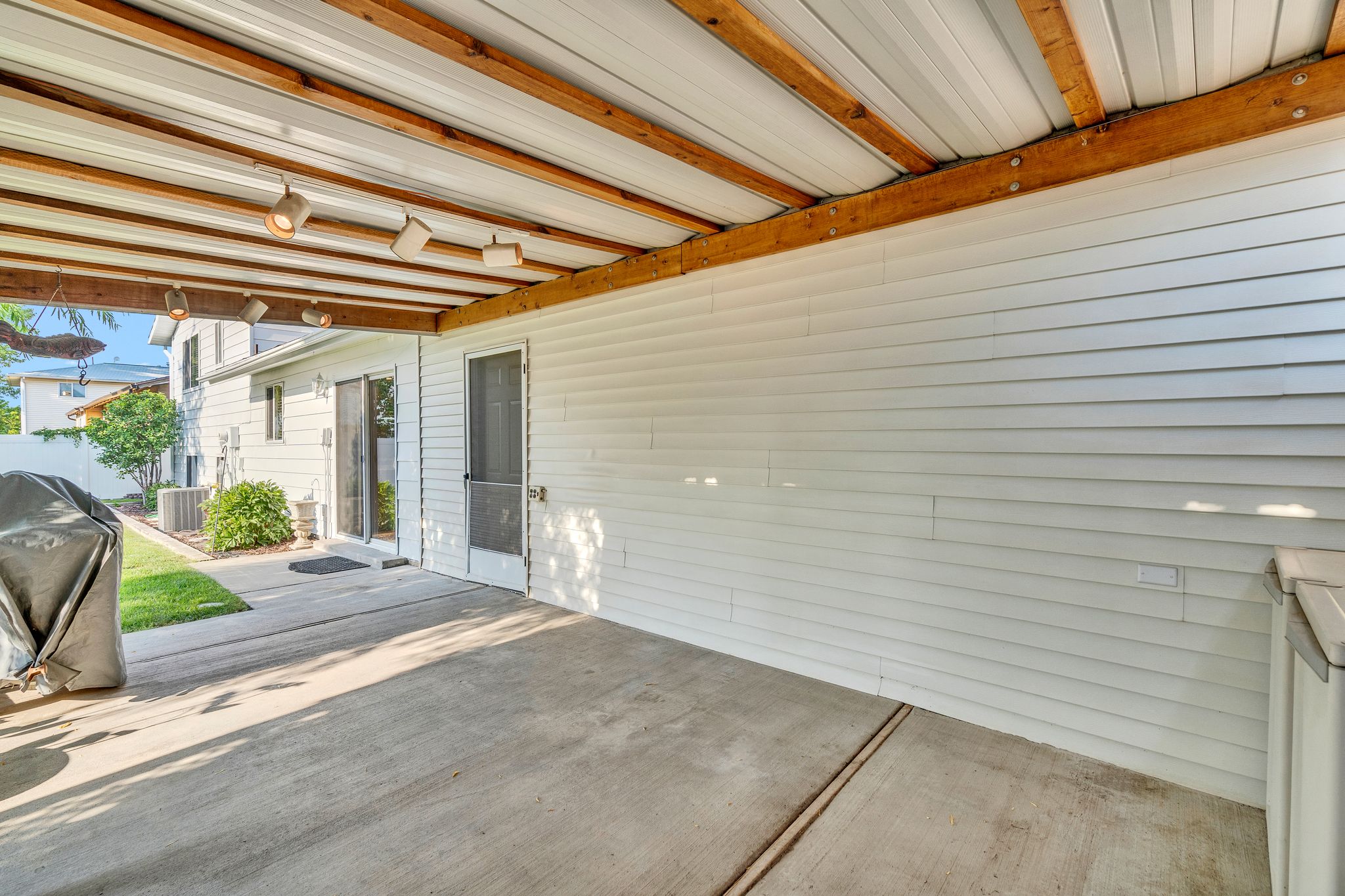 Covered patio featuring a concrete slab, white horizontal siding, and exposed wood beams