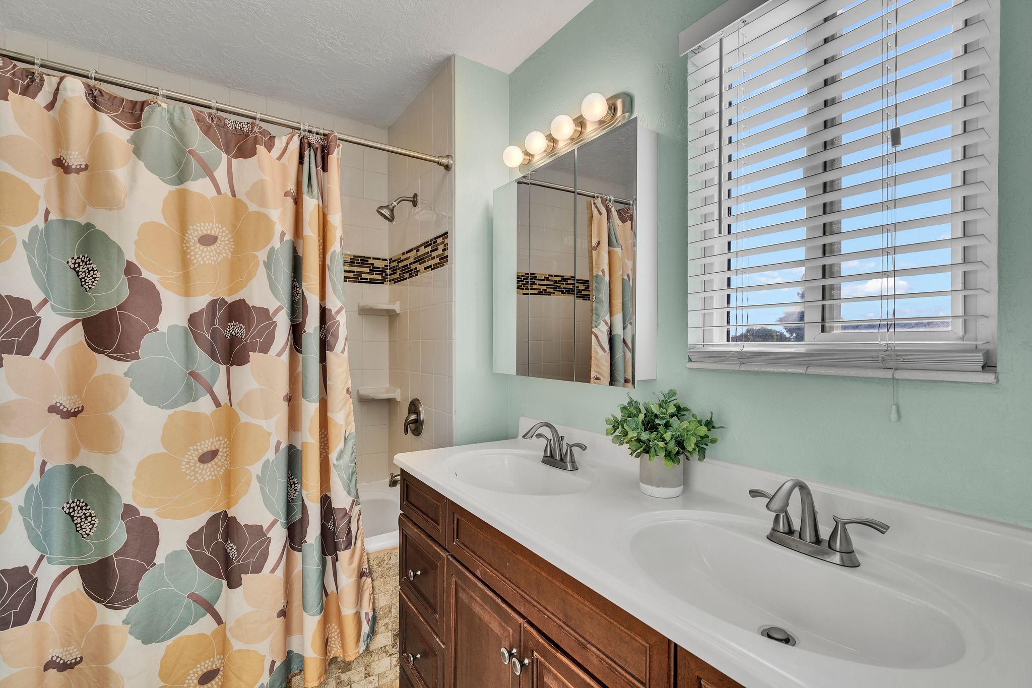 Bathroom featuring a double vanity with integrated sinks, a wood-finish cabinet, and a large mirror with integrated lighting