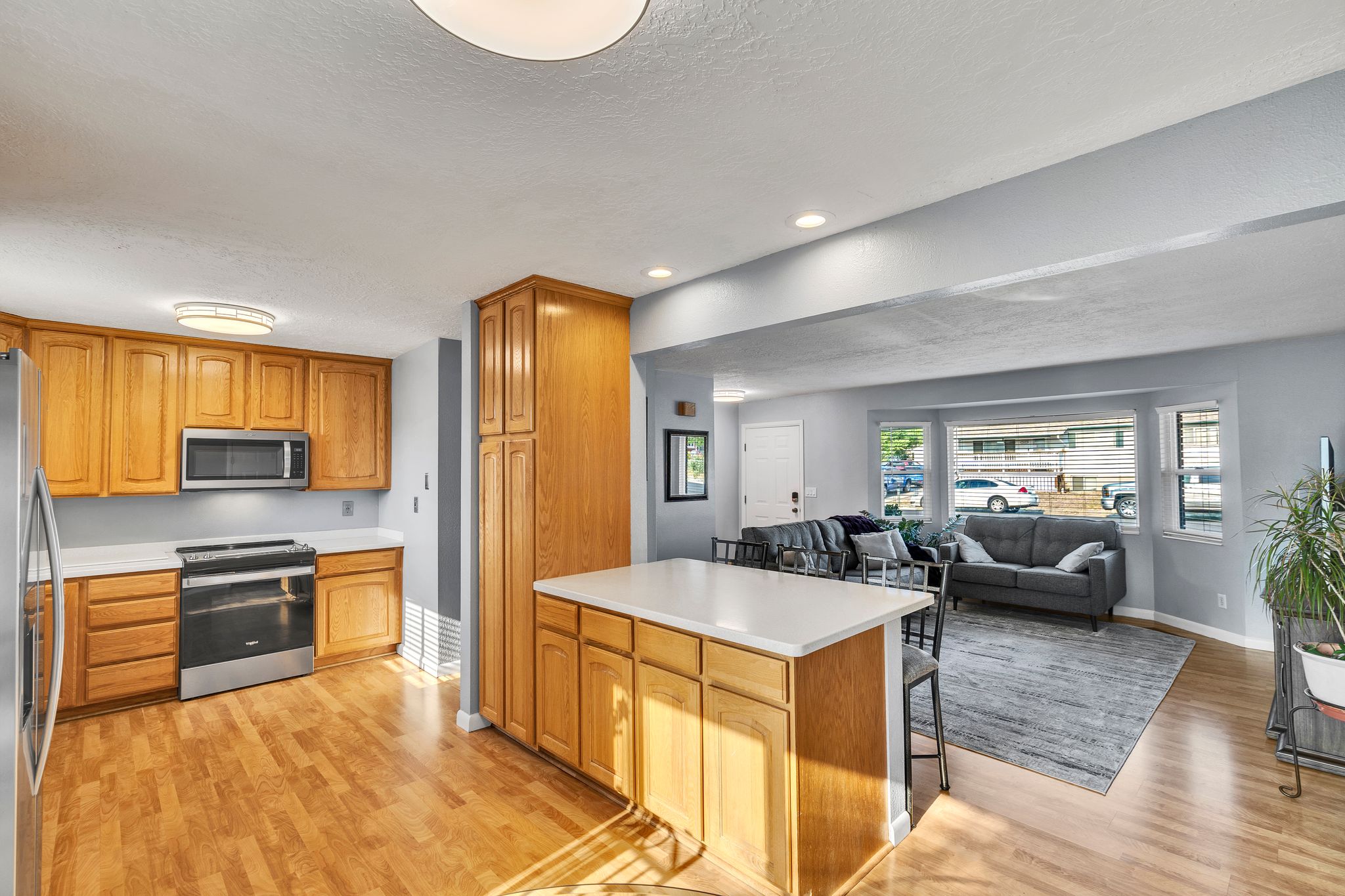 Kitchen featuring wood cabinetry, stainless steel appliances, a center island with a white countertop, and wood-finish flooring