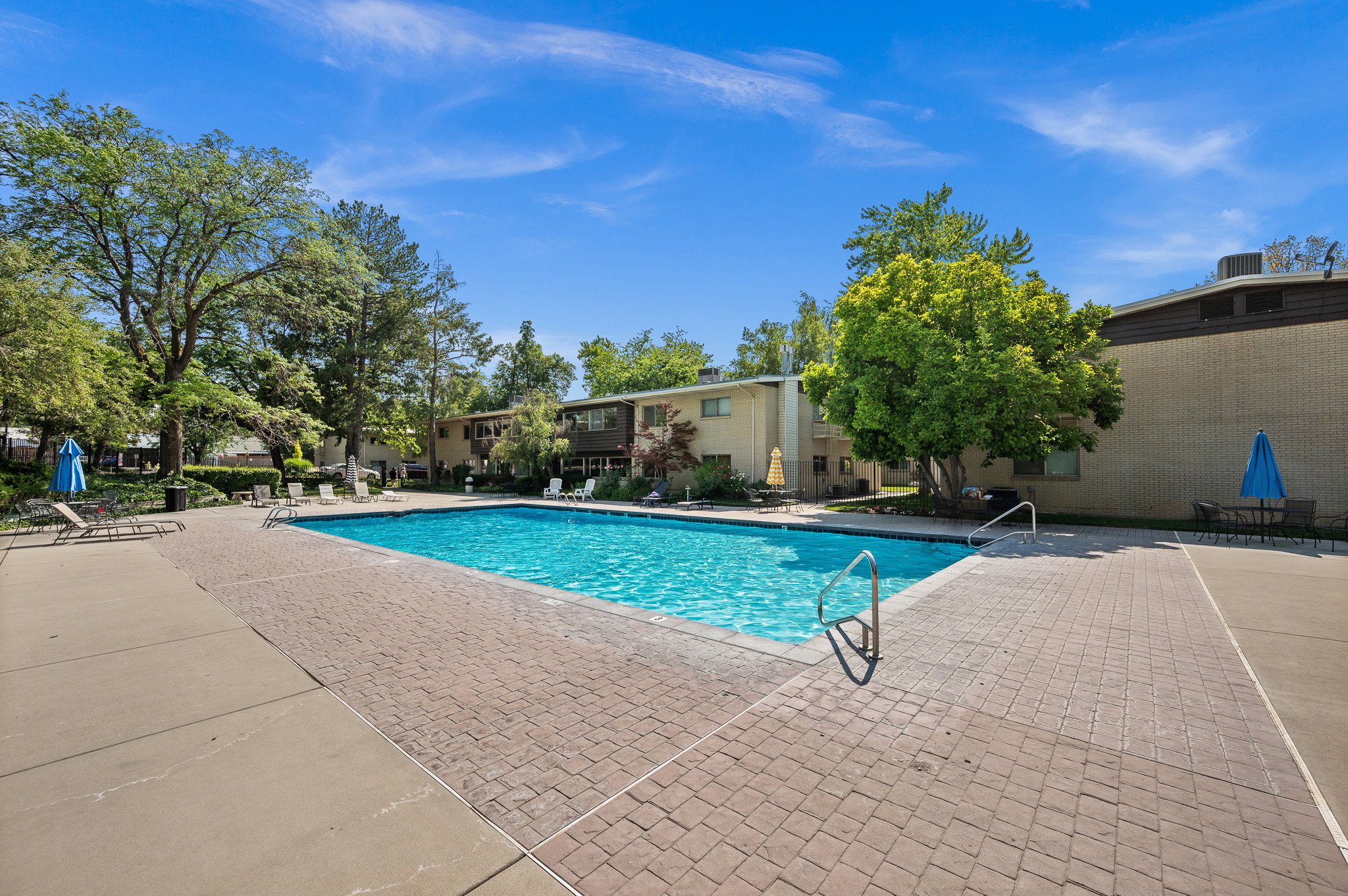 Rectangular swimming pool surrounded by a brick paver deck and concrete walkways