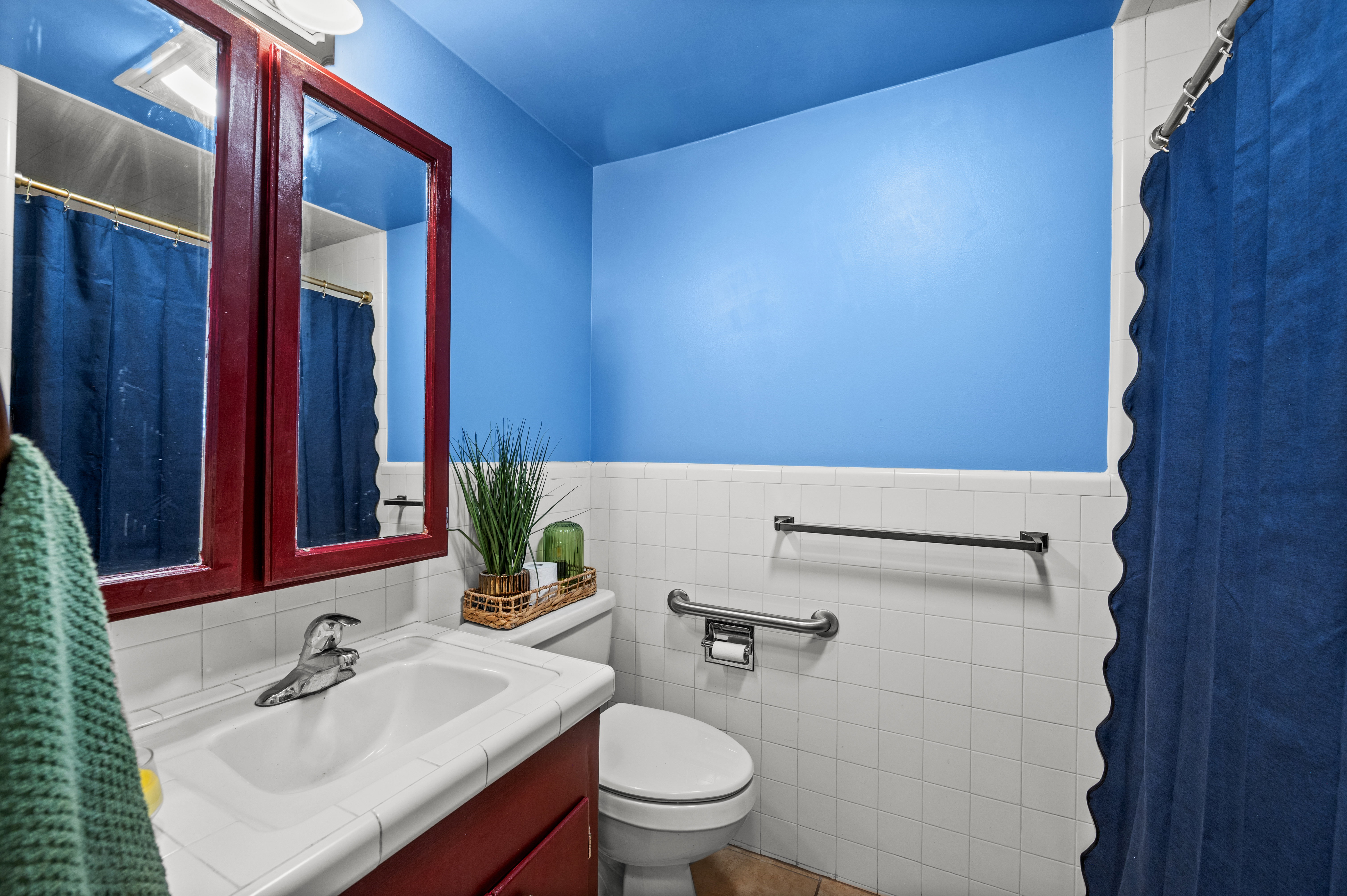 Bathroom featuring a vanity with a white countertop and integrated sink, a dark wood-finish medicine cabinet with mirrored doors, and white square wall tiles