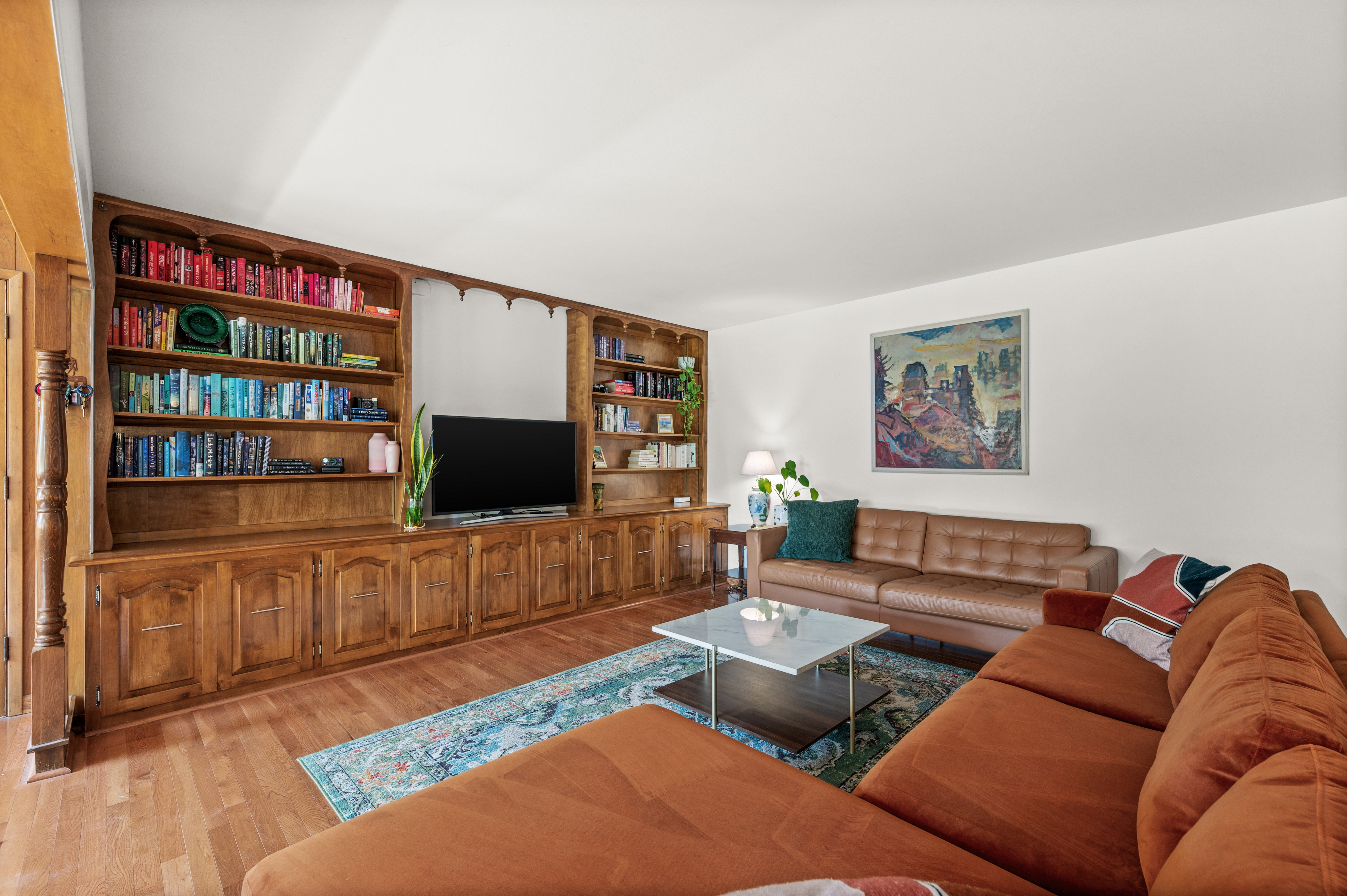 Living area featuring extensive built-in custom cabinetry and shelving, wood-finish flooring, and bright white walls