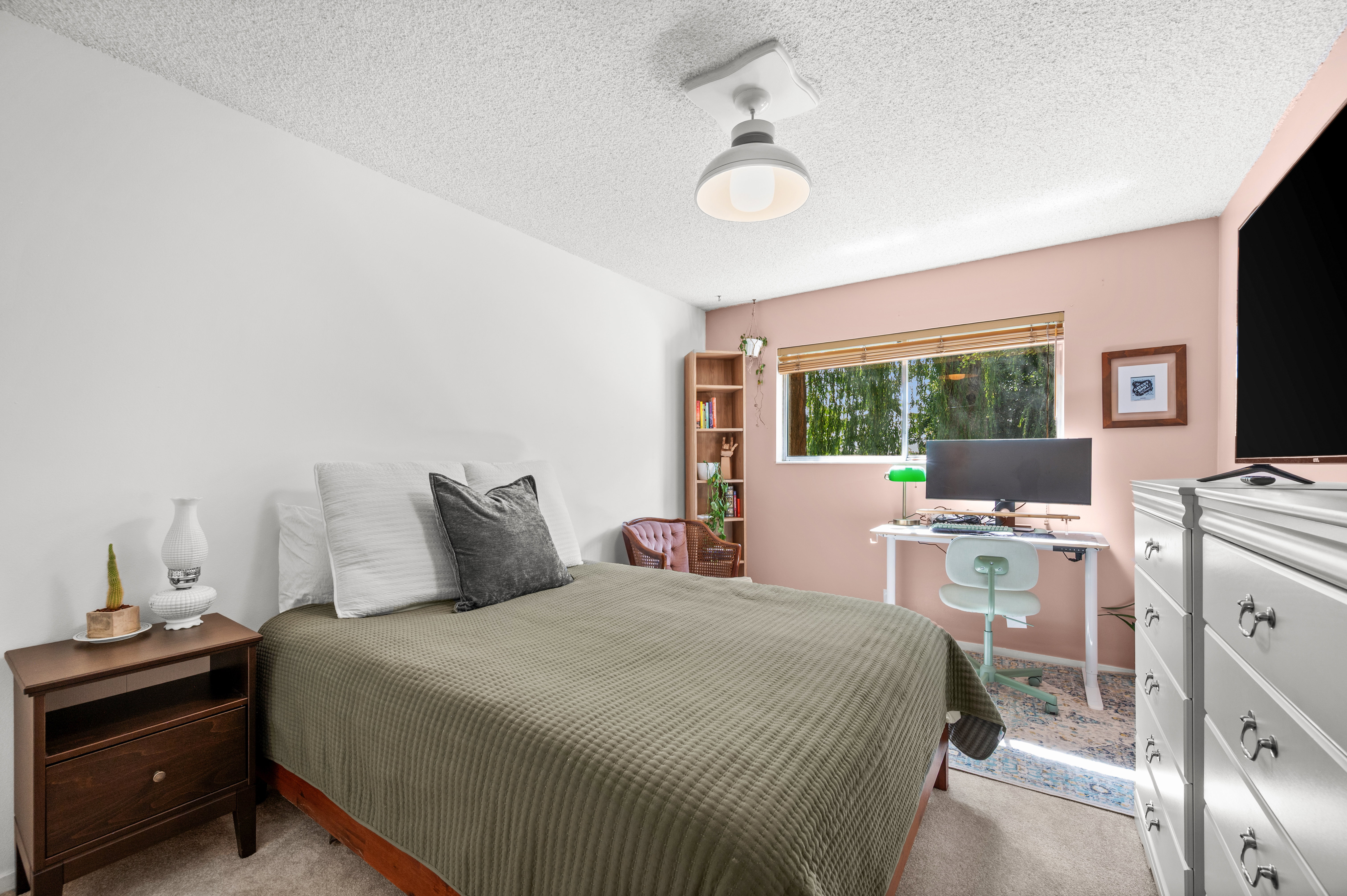 Bedroom featuring a window with bamboo blinds, a built-in wooden bookshelf, and a ceiling-mounted light fixture