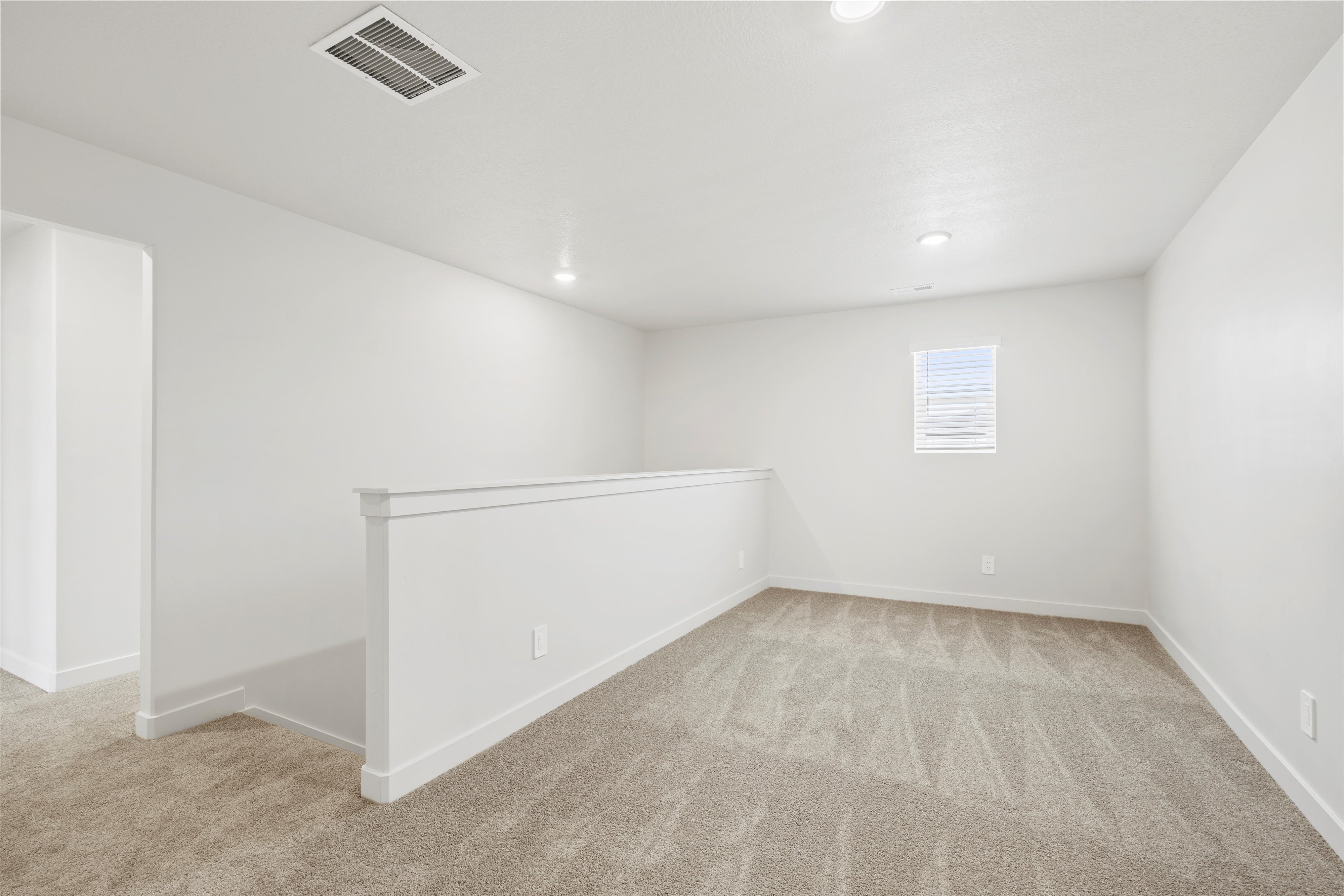 **DISCLAIMER** Interior package may vary. Carpeted upper-level bonus room with a window featuring blinds, recessed lighting, and a white half-wall