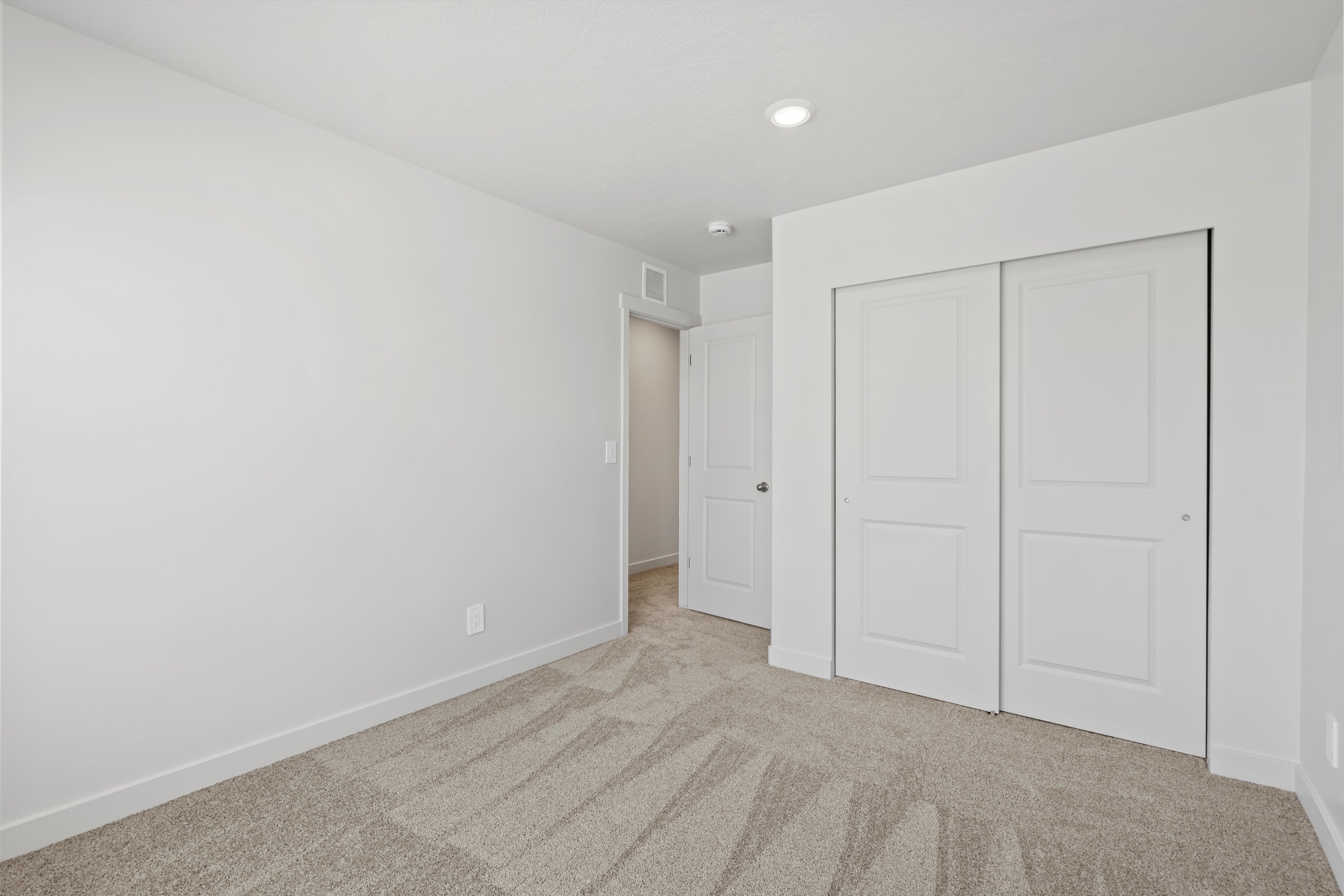 **DISCLAIMER** Interior package may vary. Carpeted room featuring a double sliding door closet with panel detailing, a recessed ceiling light, and a white baseboard trim