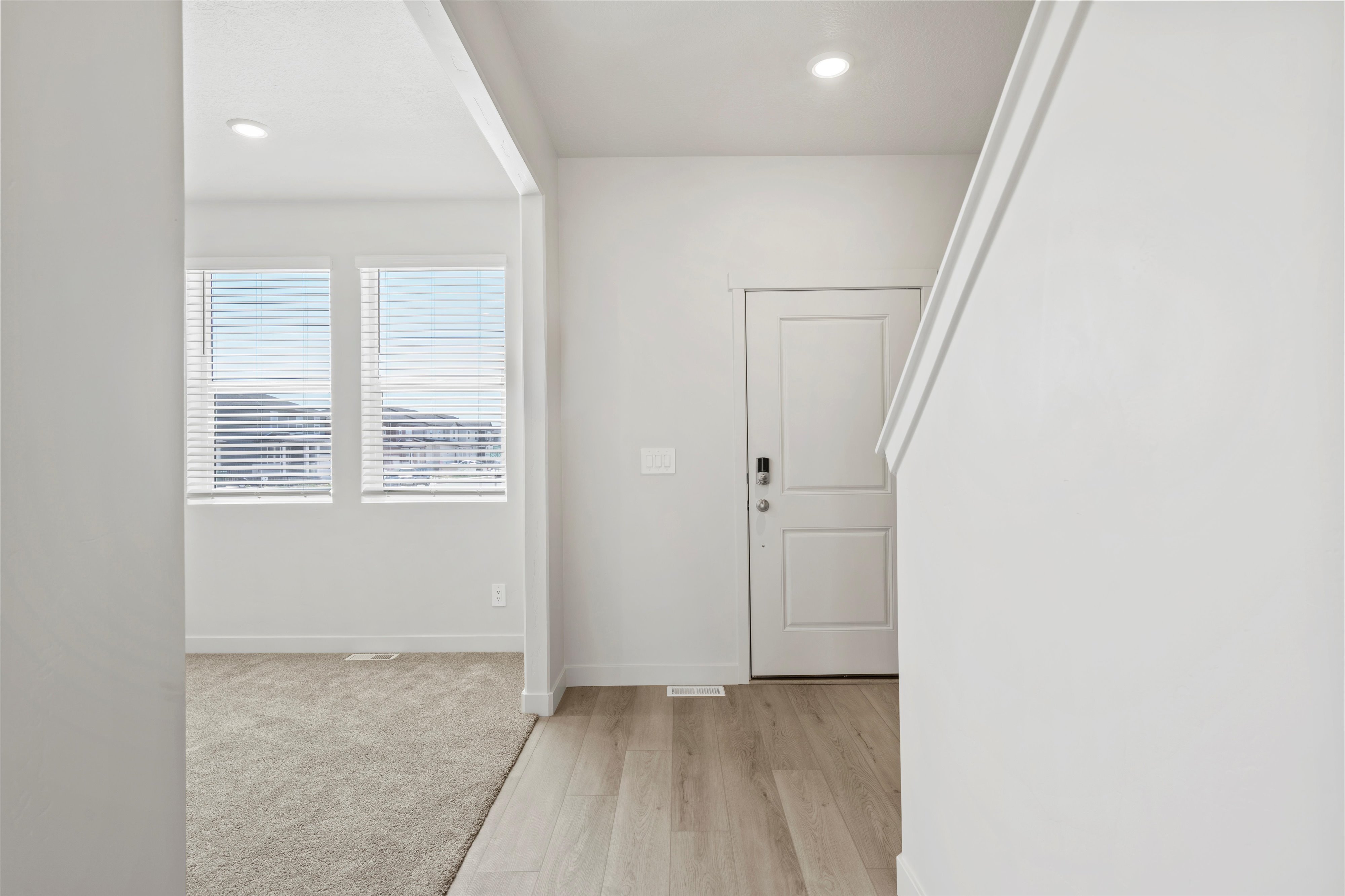 **DISCLAIMER** Interior package may vary. Entryway featuring light wood-finish flooring, a white paneled door with smart lock hardware, and recessed lighting