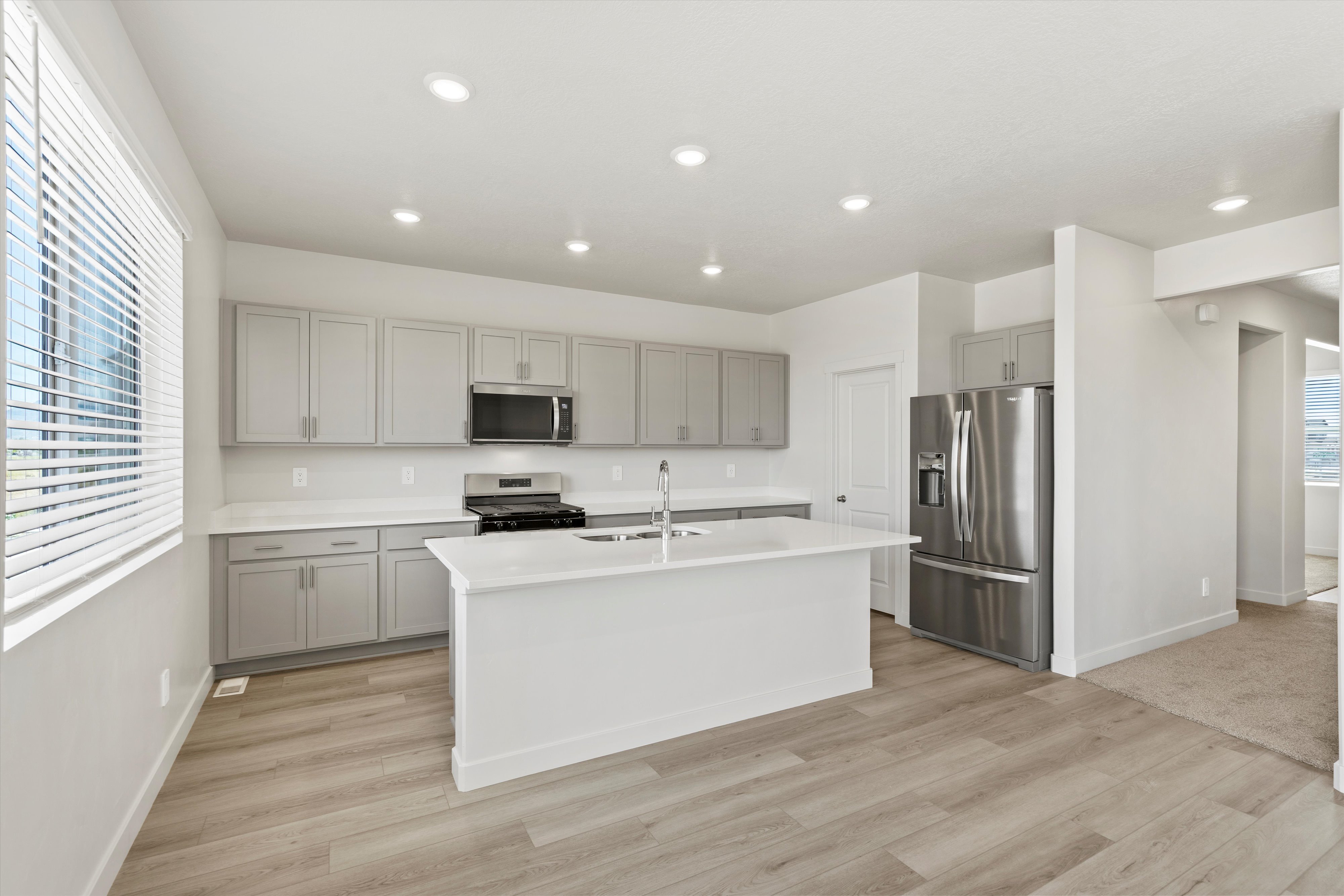 **DISCLAIMER** Interior package may vary. Kitchen featuring a central island, light gray cabinetry, white countertops, and stainless steel appliances