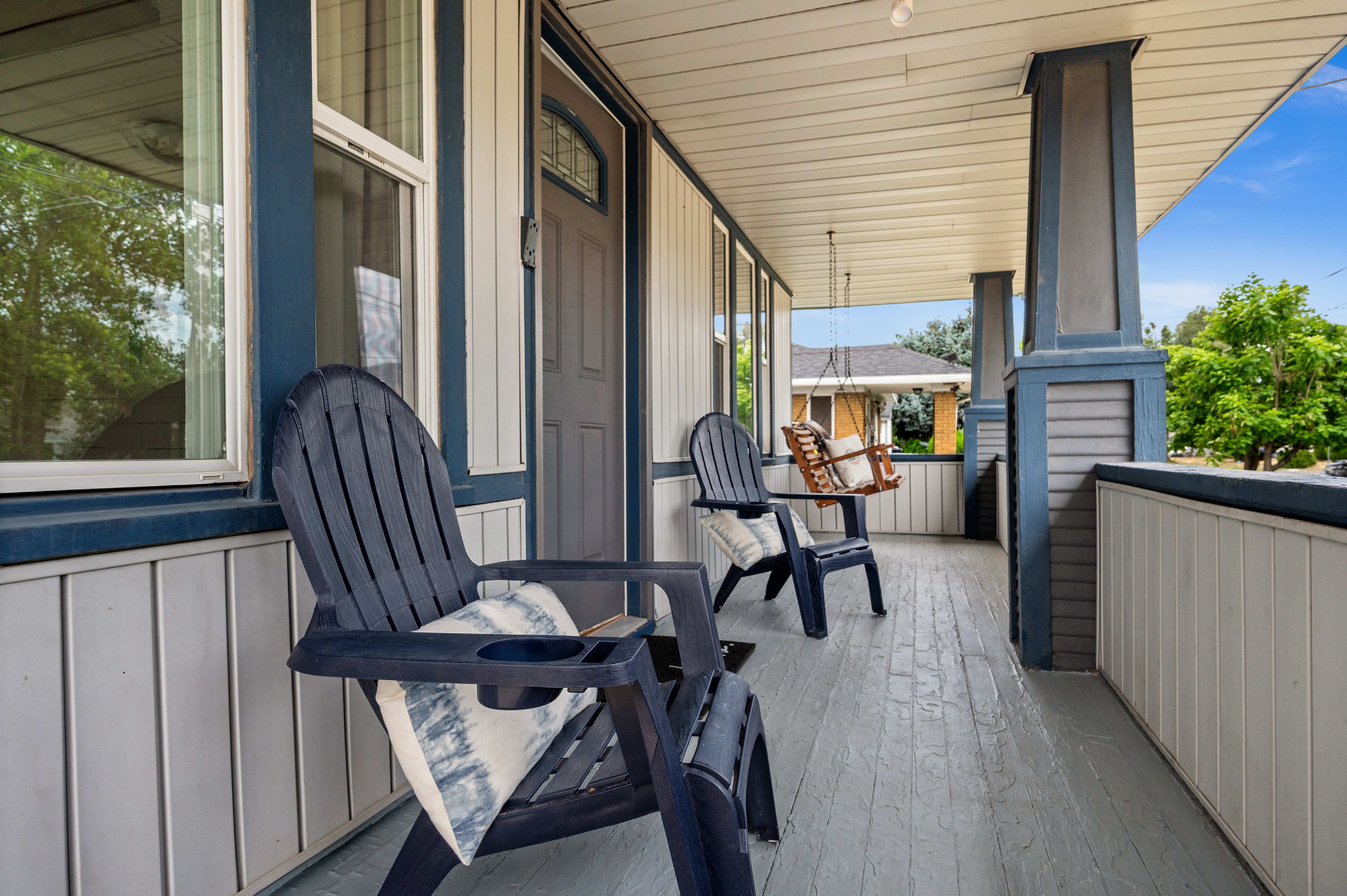 Inviting covered porch featuring a painted wood-finish floor, vertical panel siding, and decorative columns